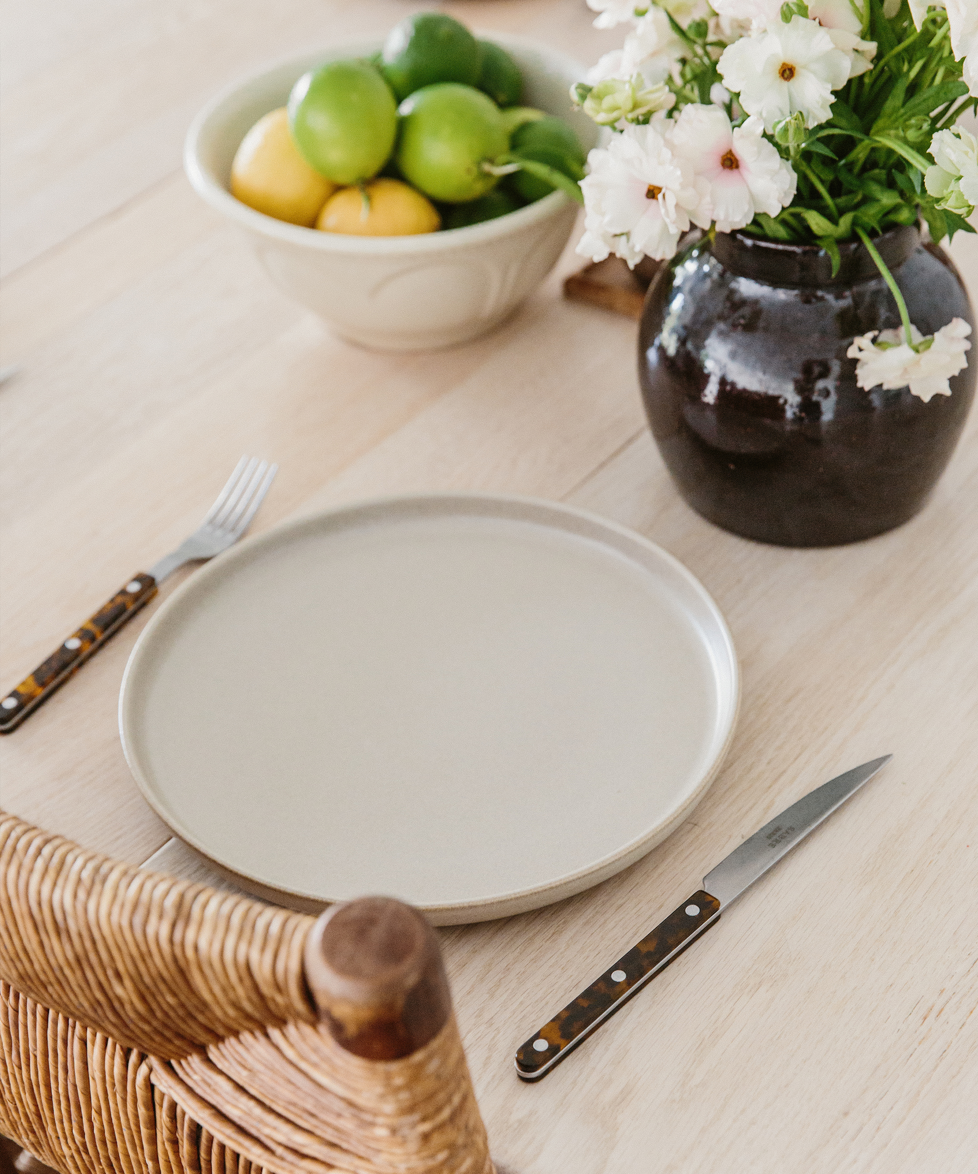 place setting on oak table with taupe plate and tortoise cutlery