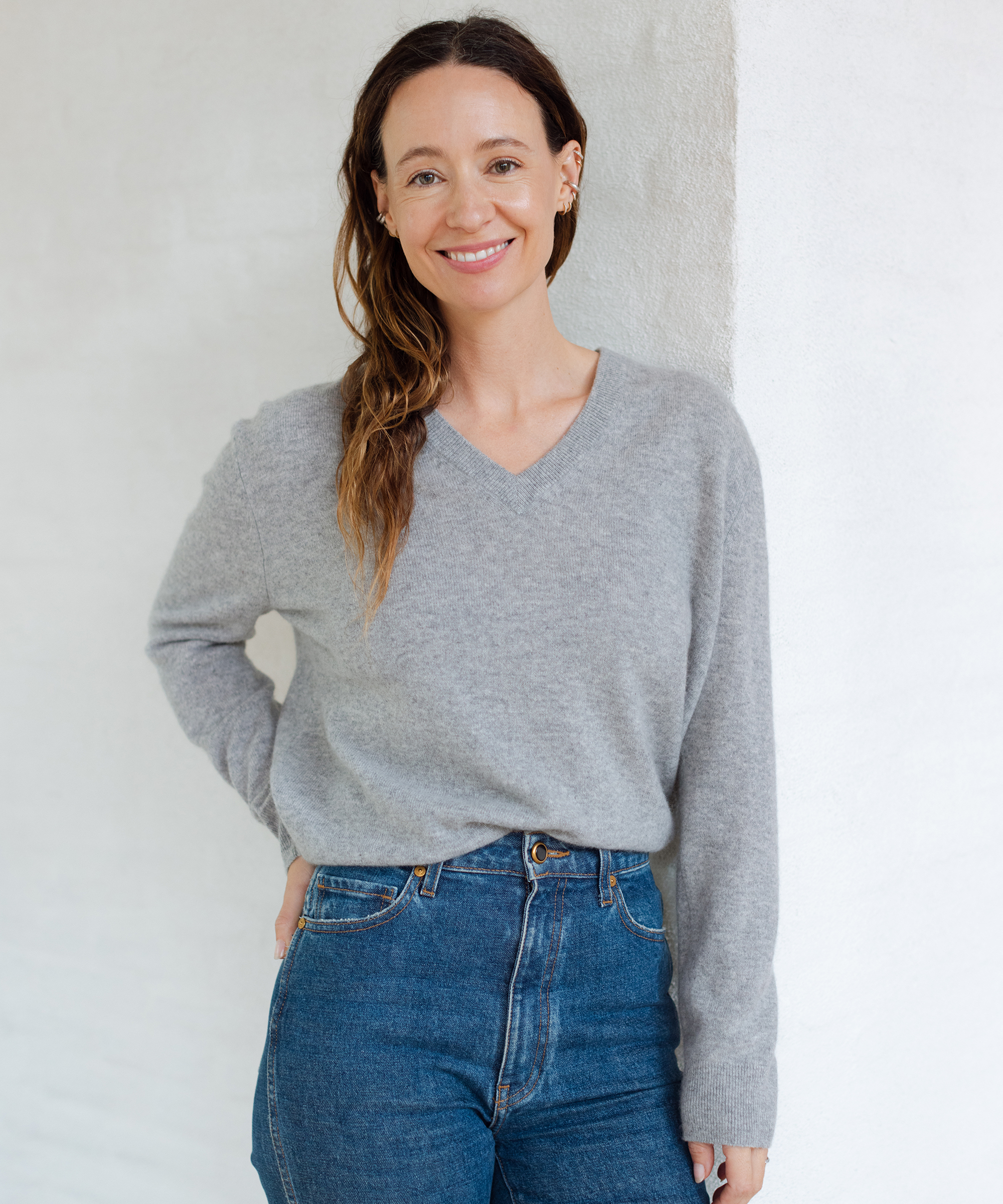 jenni kayne standing with hand on hip in grey v-neck cashmere sweater