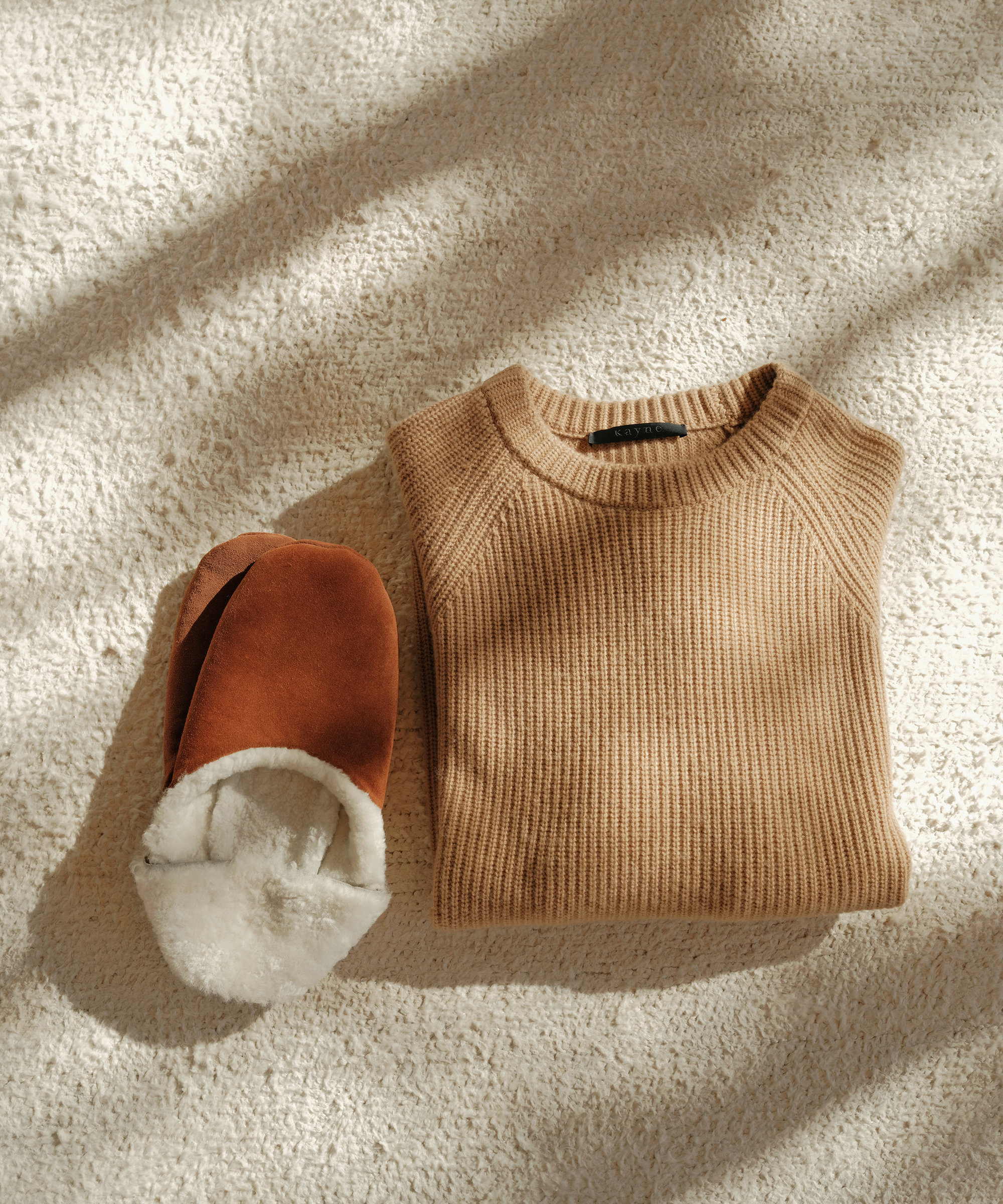 mens folded sweater and chestnut suede slippers on ivory carpet with shadows