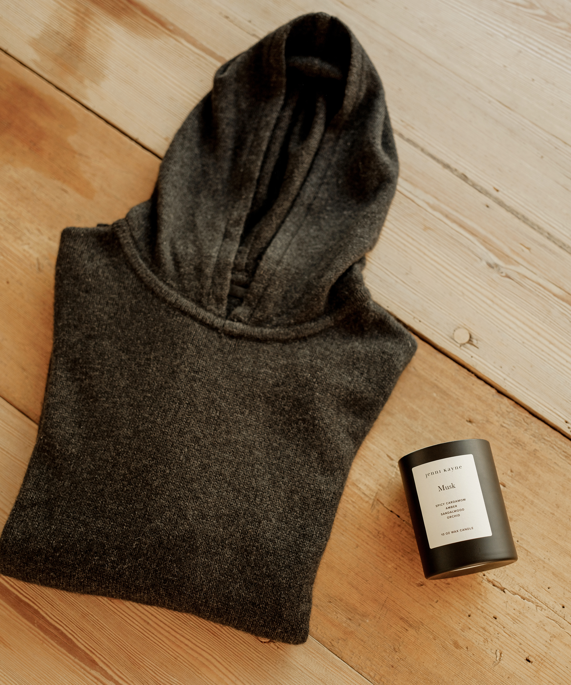 oak table with folded mens dark grey hoodie and musk candle