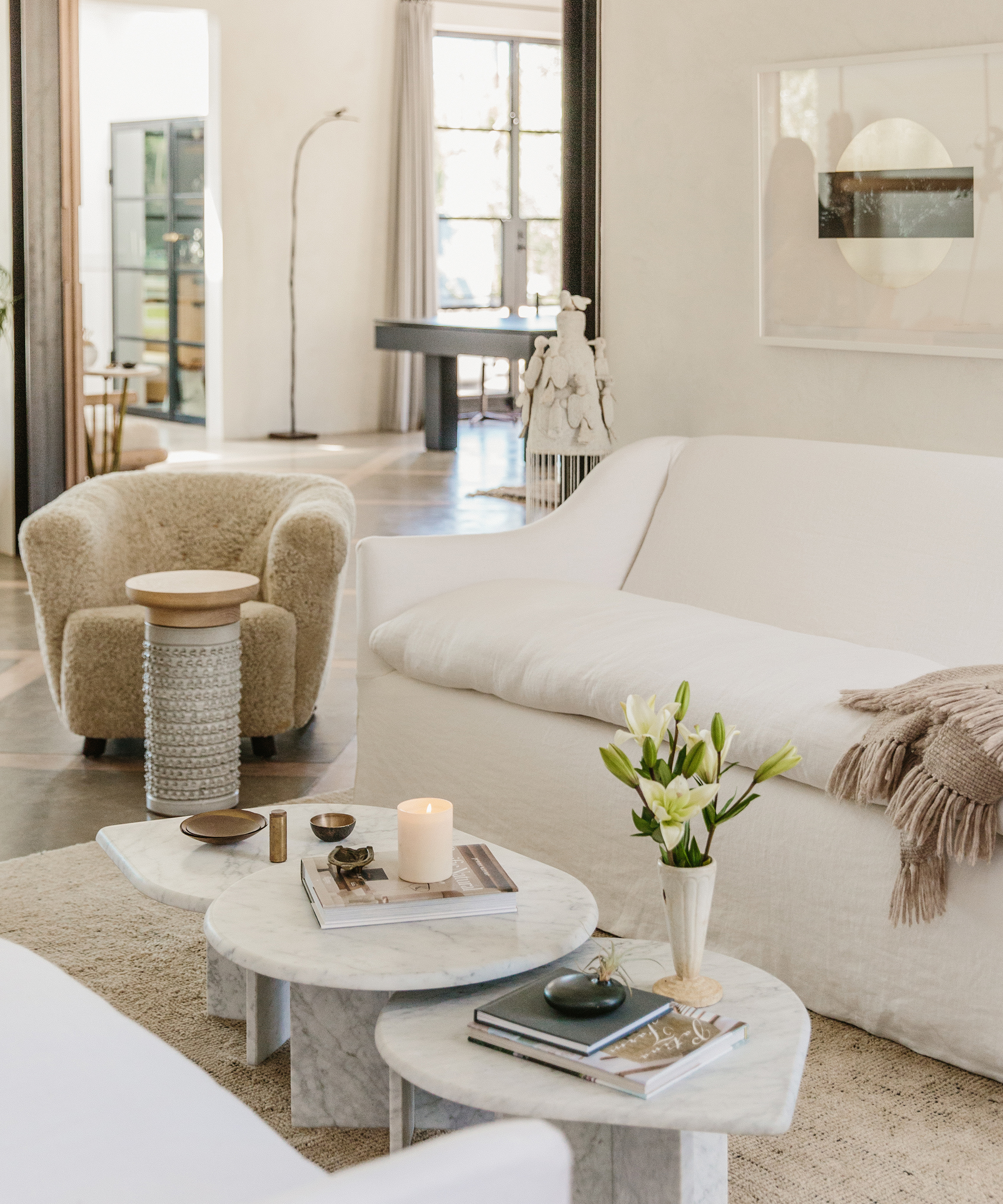 white couch and stacked coffee table with a small boucle accent chair