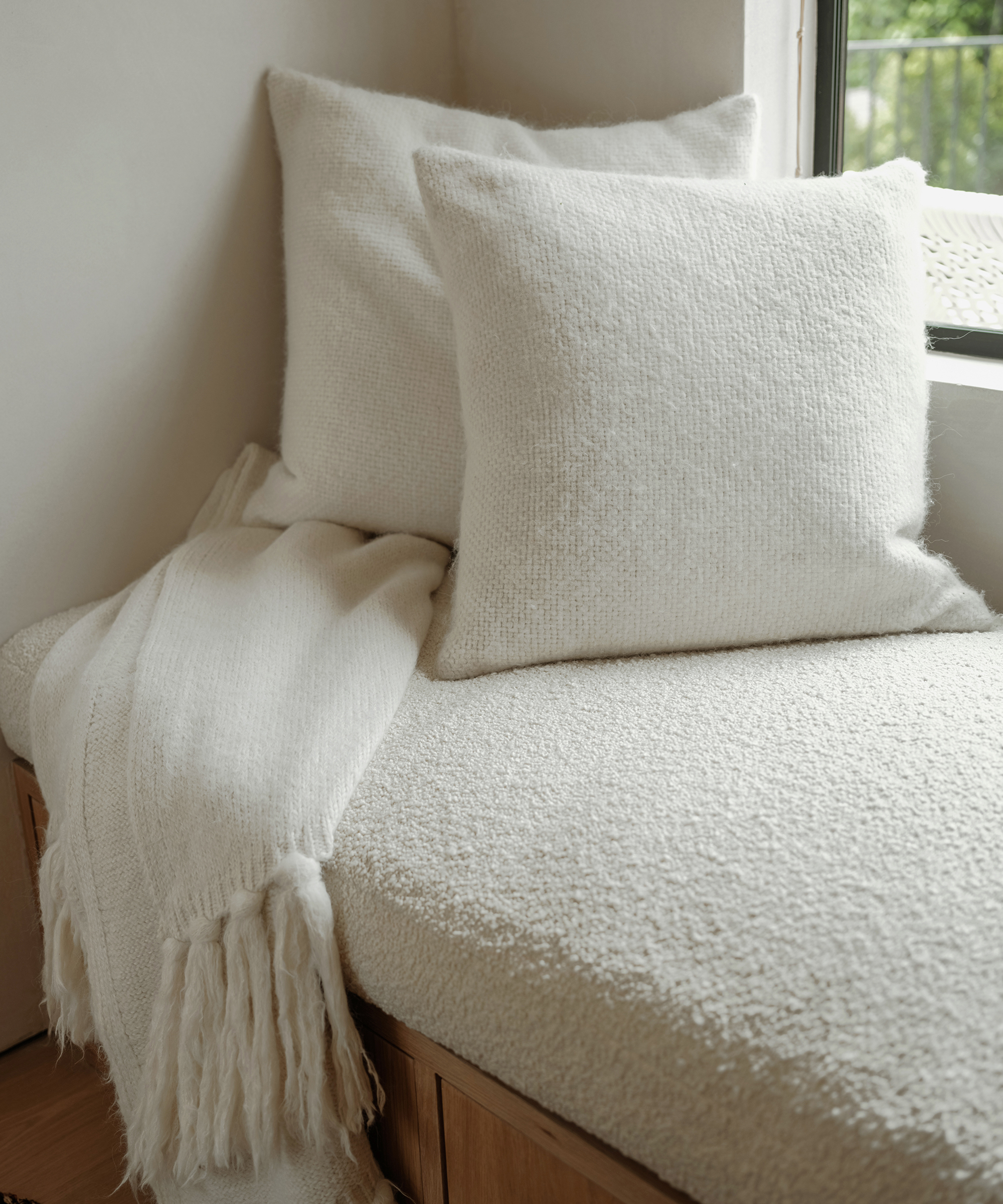 two ivory alpaca basketweave pillows with a mohair throw and built-in boucle bench