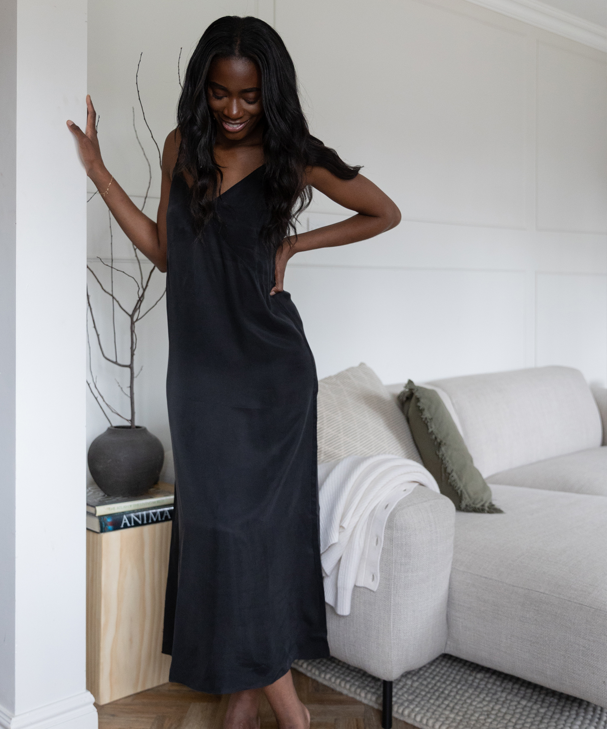 a woman leaning against a wall in a black maxi dress