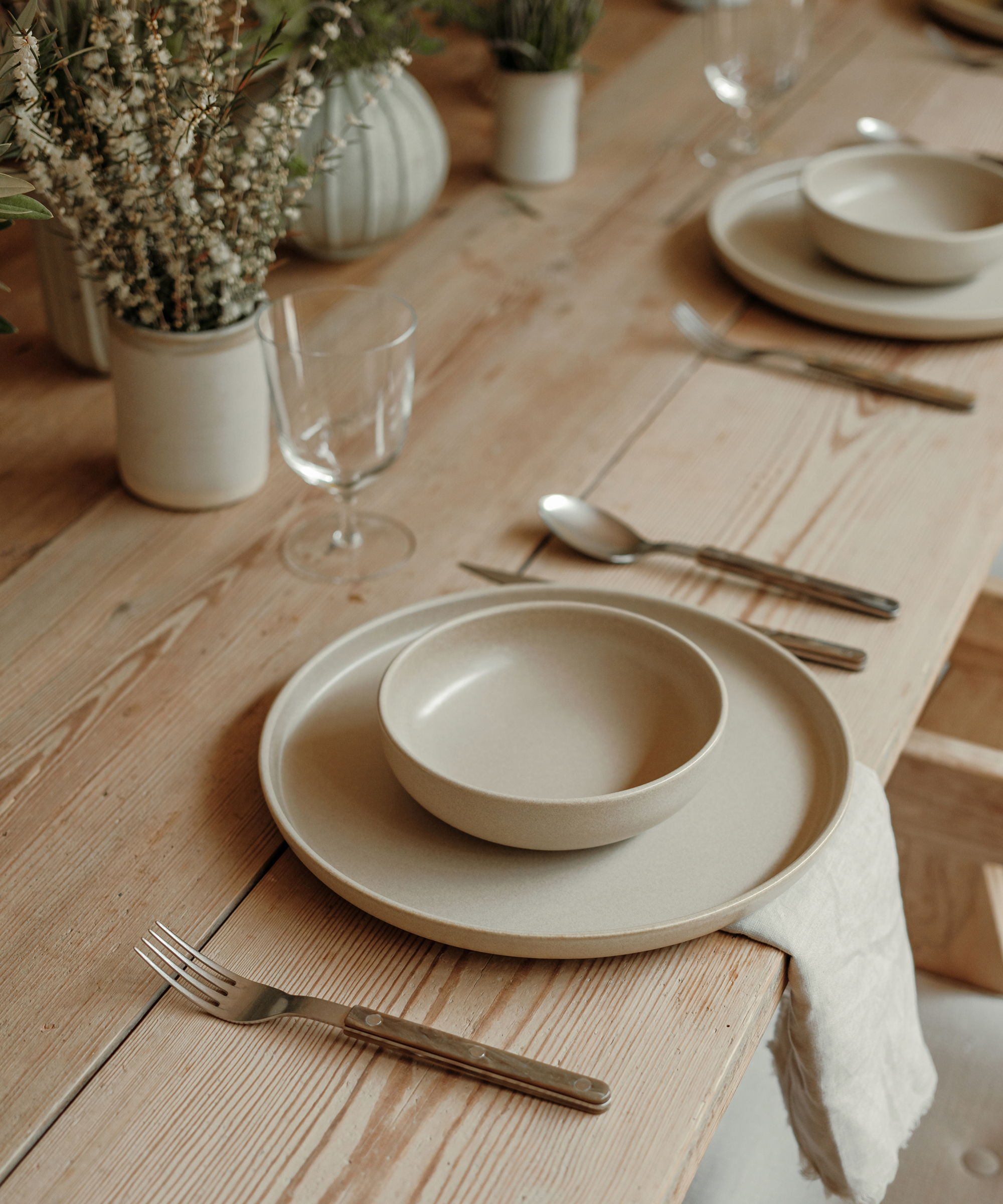 oak dining table with taupe dinner plate and bowl and tortoise silverware