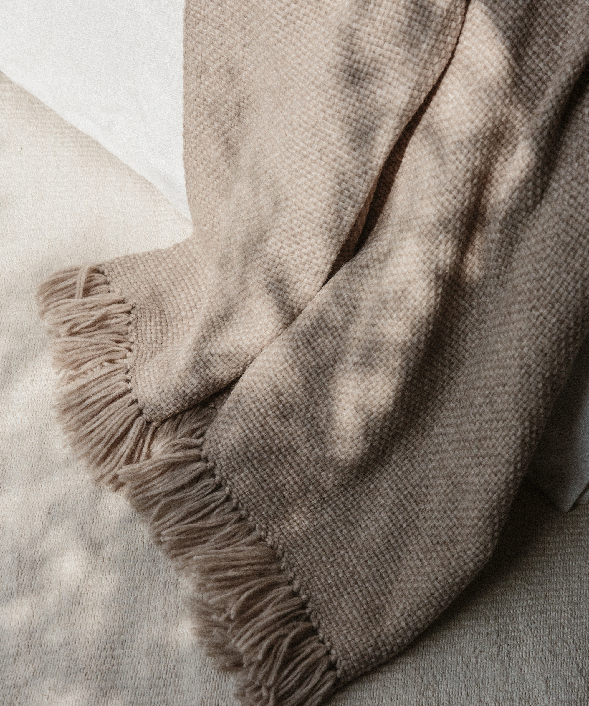 oatmeal throw draped over a chair and touching an ivory rug