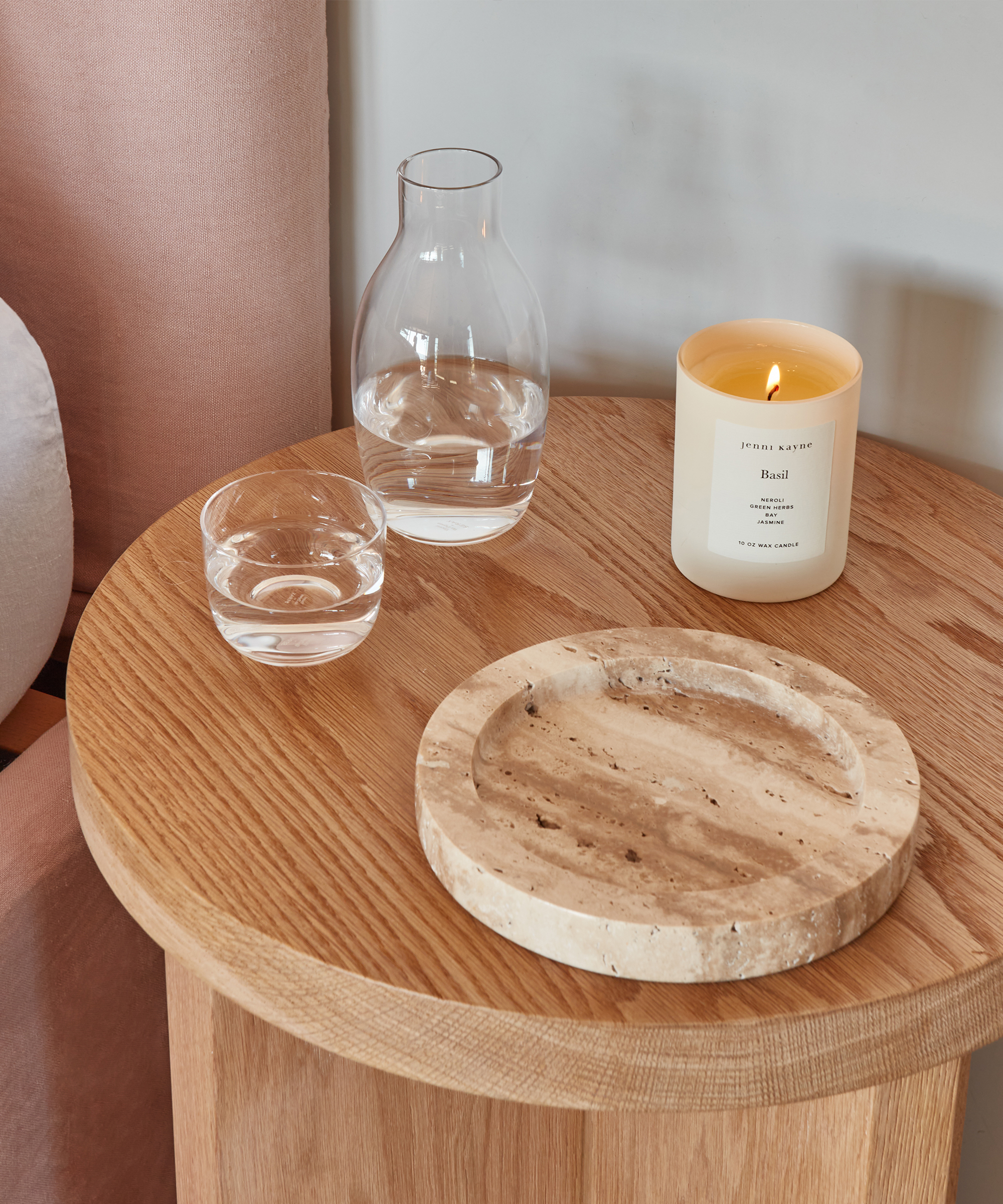 oak side table with a clear water carafe and a candle burning