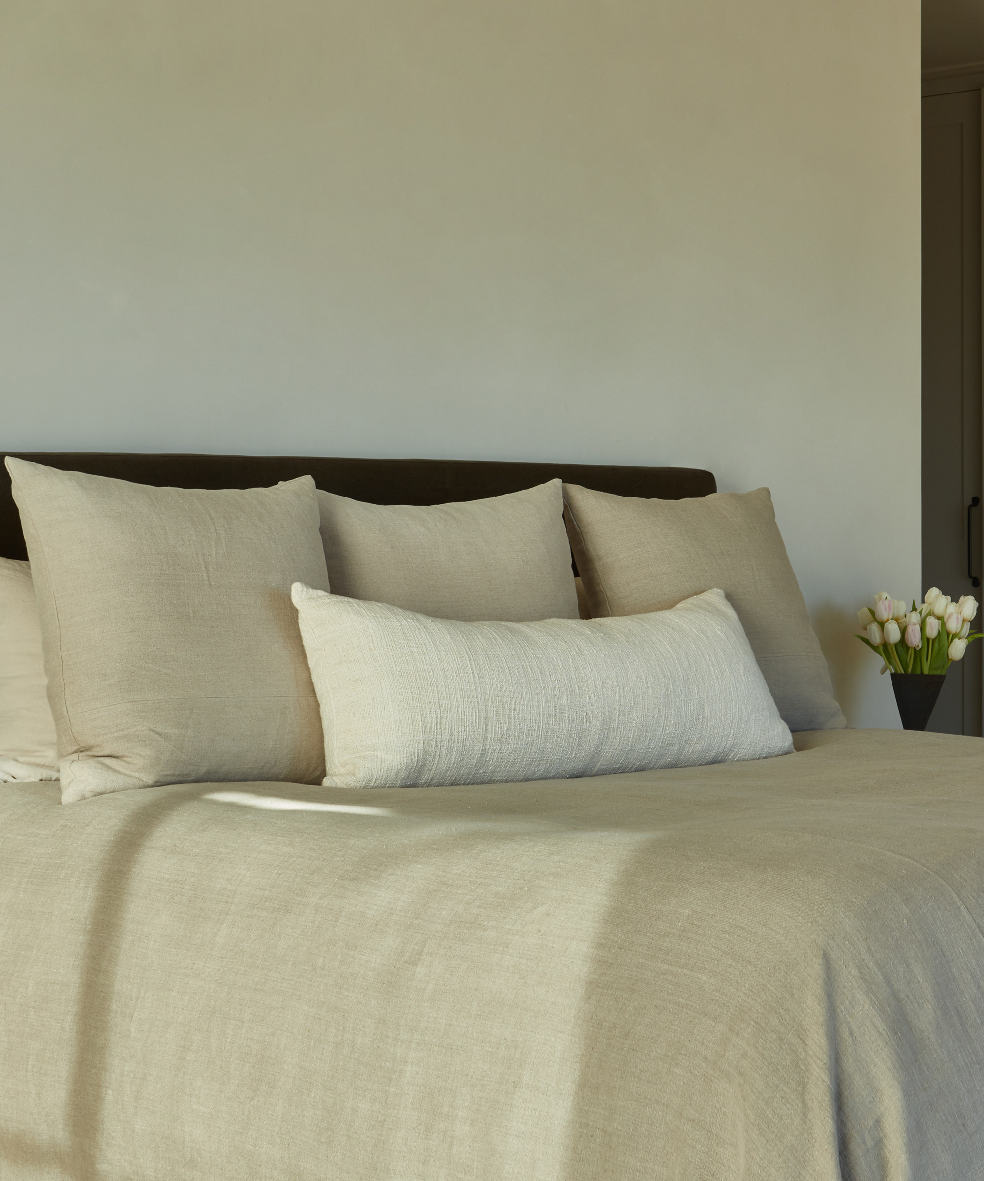close up of neutral bedding with three euro pillows and one white lumbar pillow