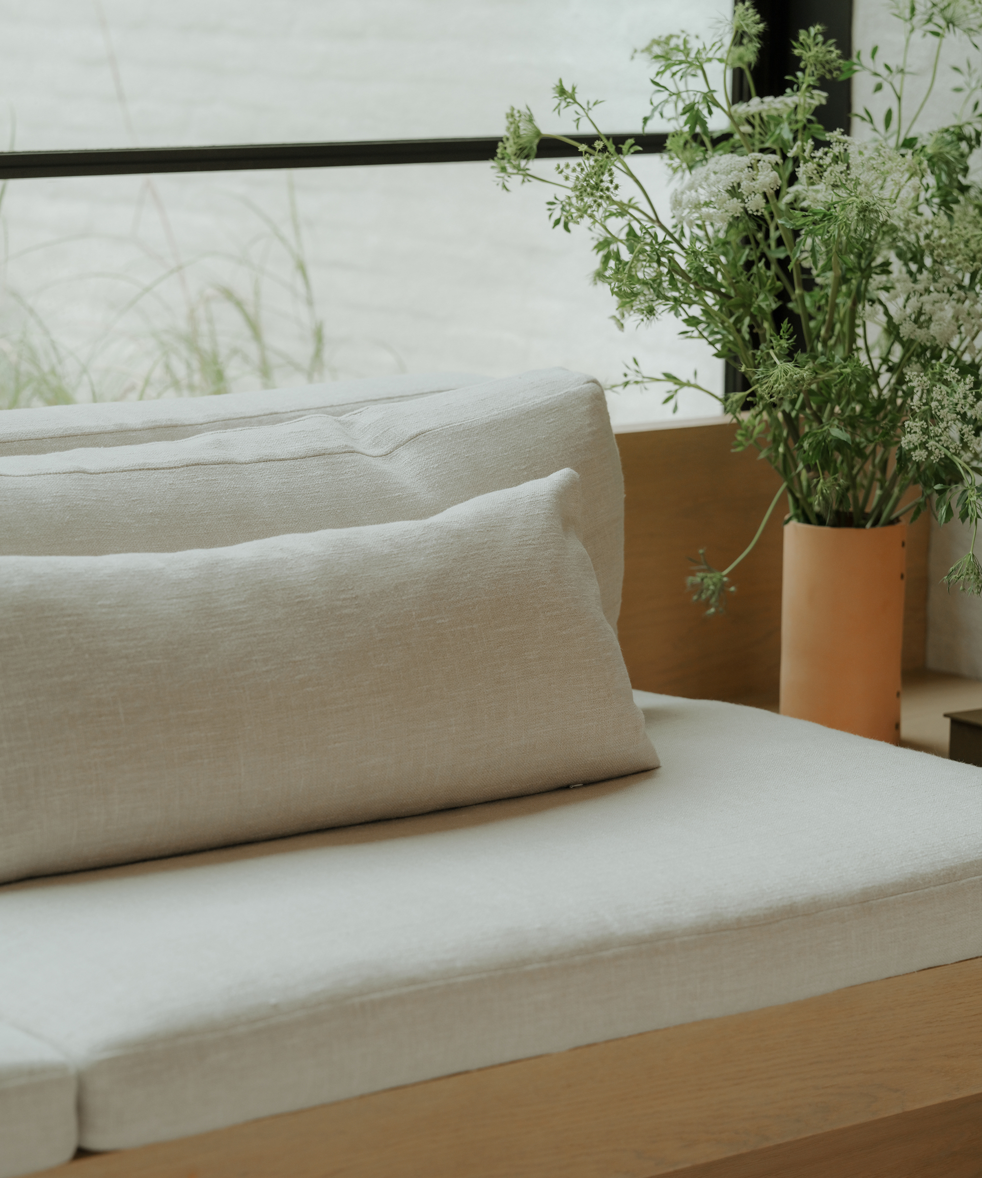 large green floral arrangement in a leather vase next to a built in couch