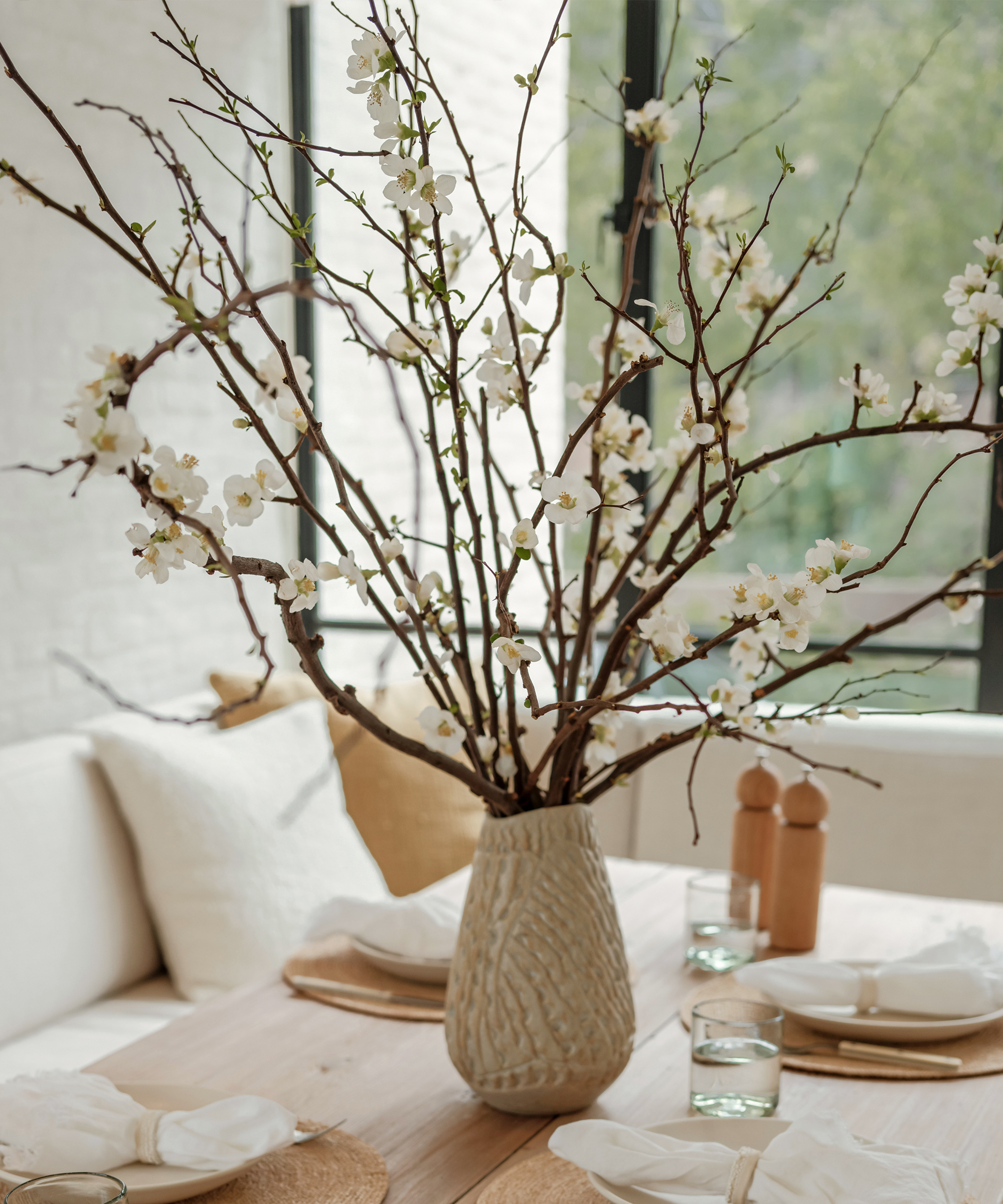 large ivory vase with flowing branches on a dining table