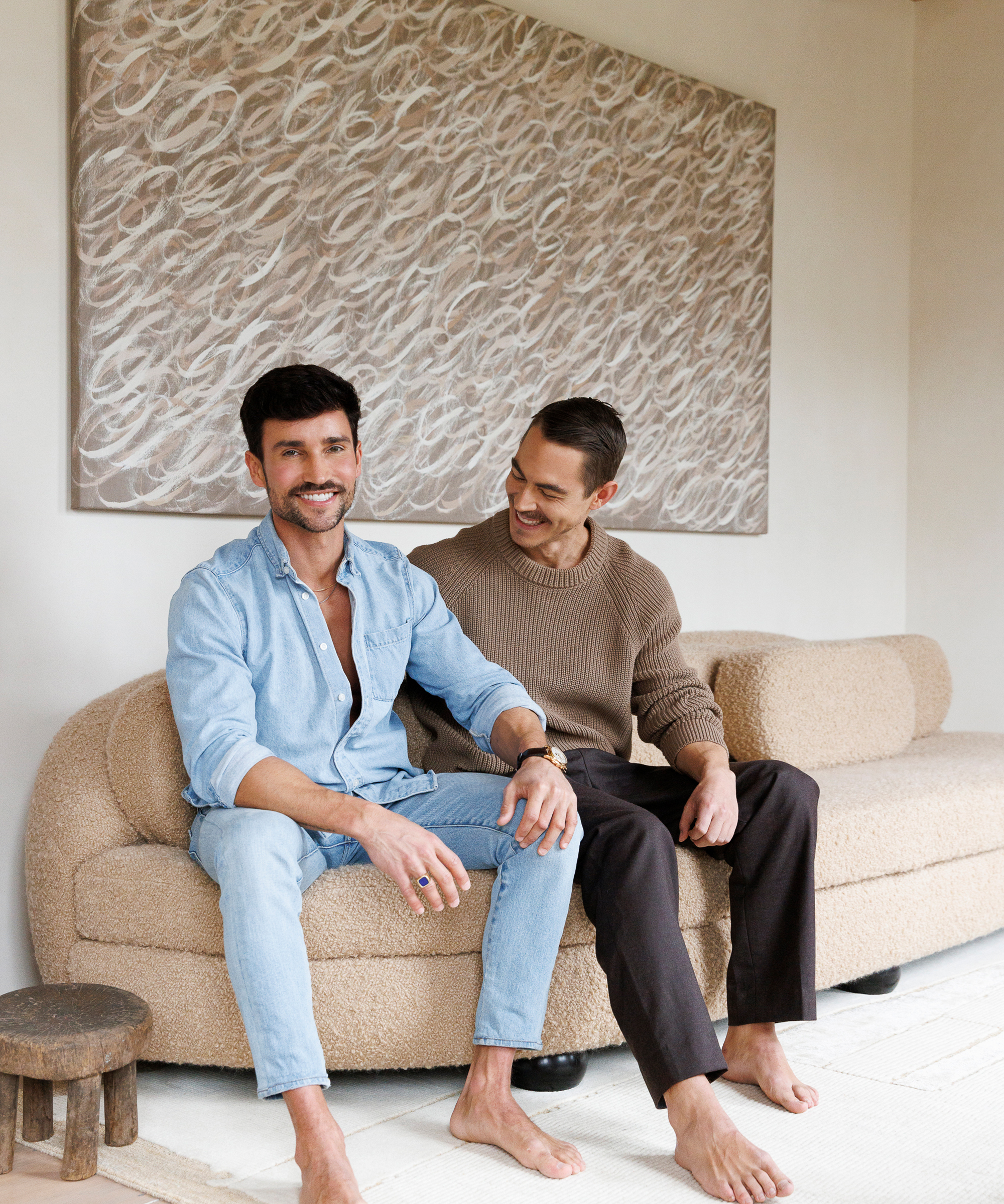 two men laughing on a curved couch