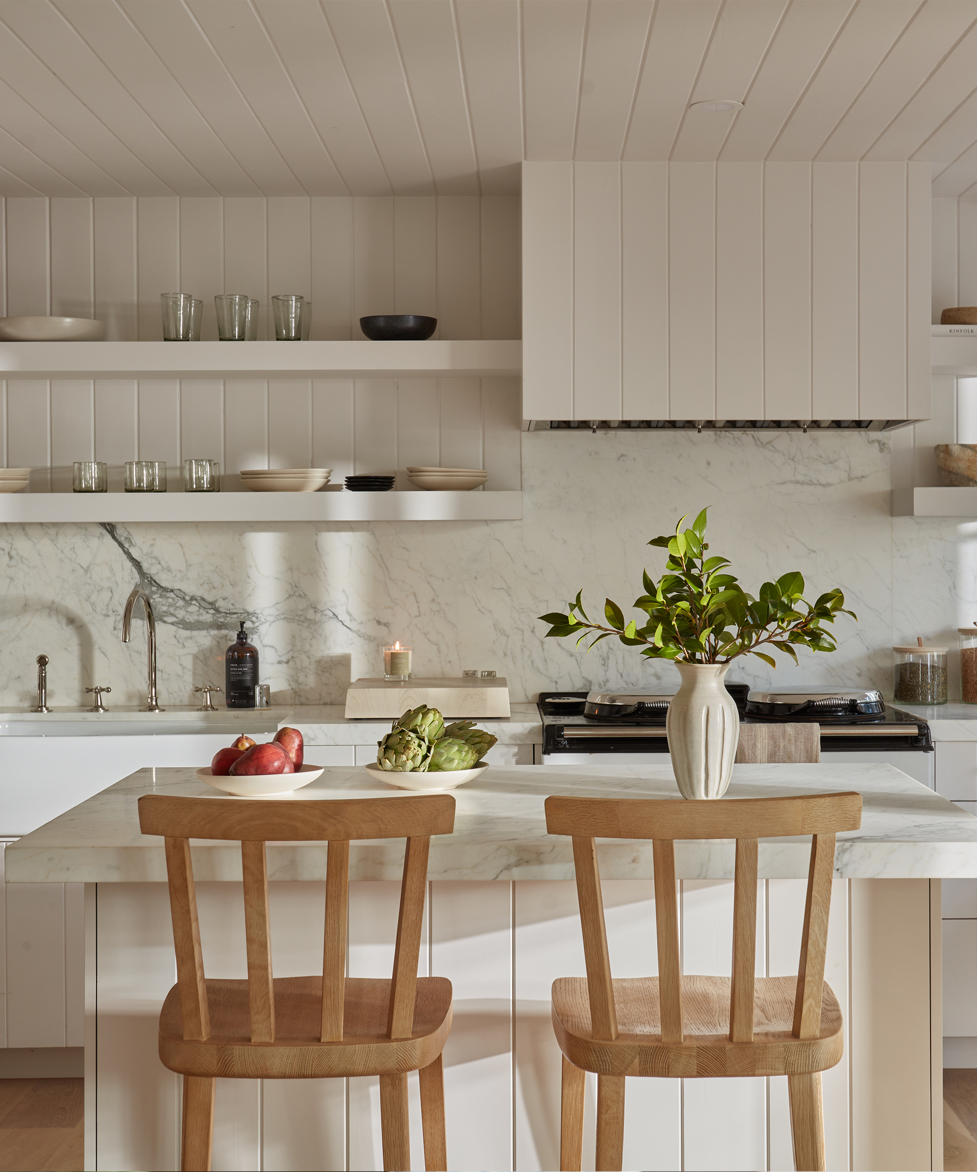 white kitchen with marble backsplash and two wooden counter stools