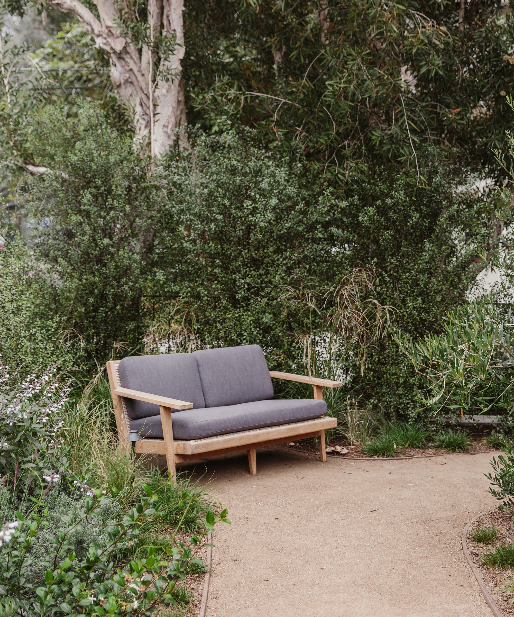 outdoor grey vista sofa in greenery on a gravel path