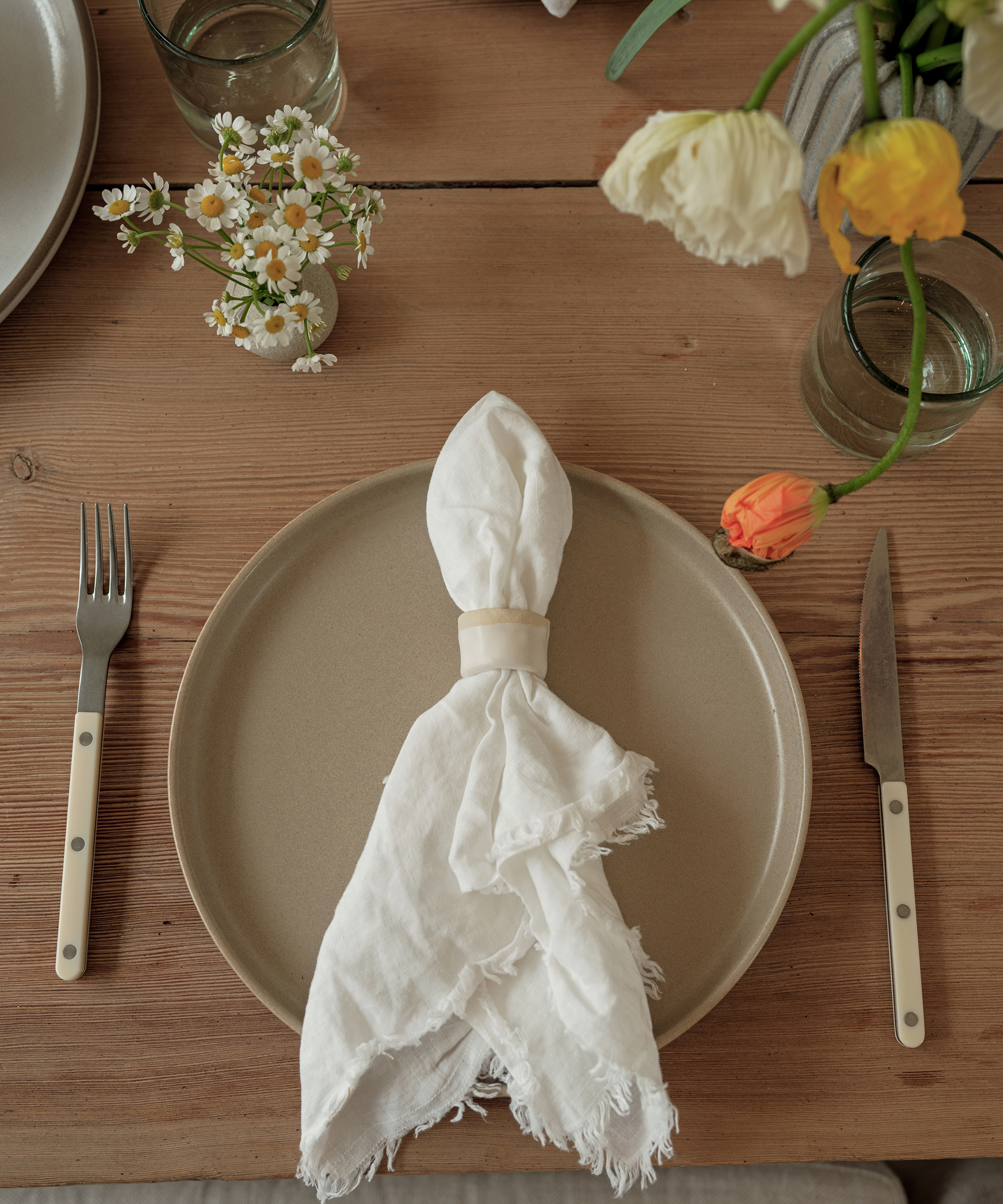 table setting with a taupe pacific plate and ivory linen napkin with a ceramic napkin ring and ivory bistro cutlery