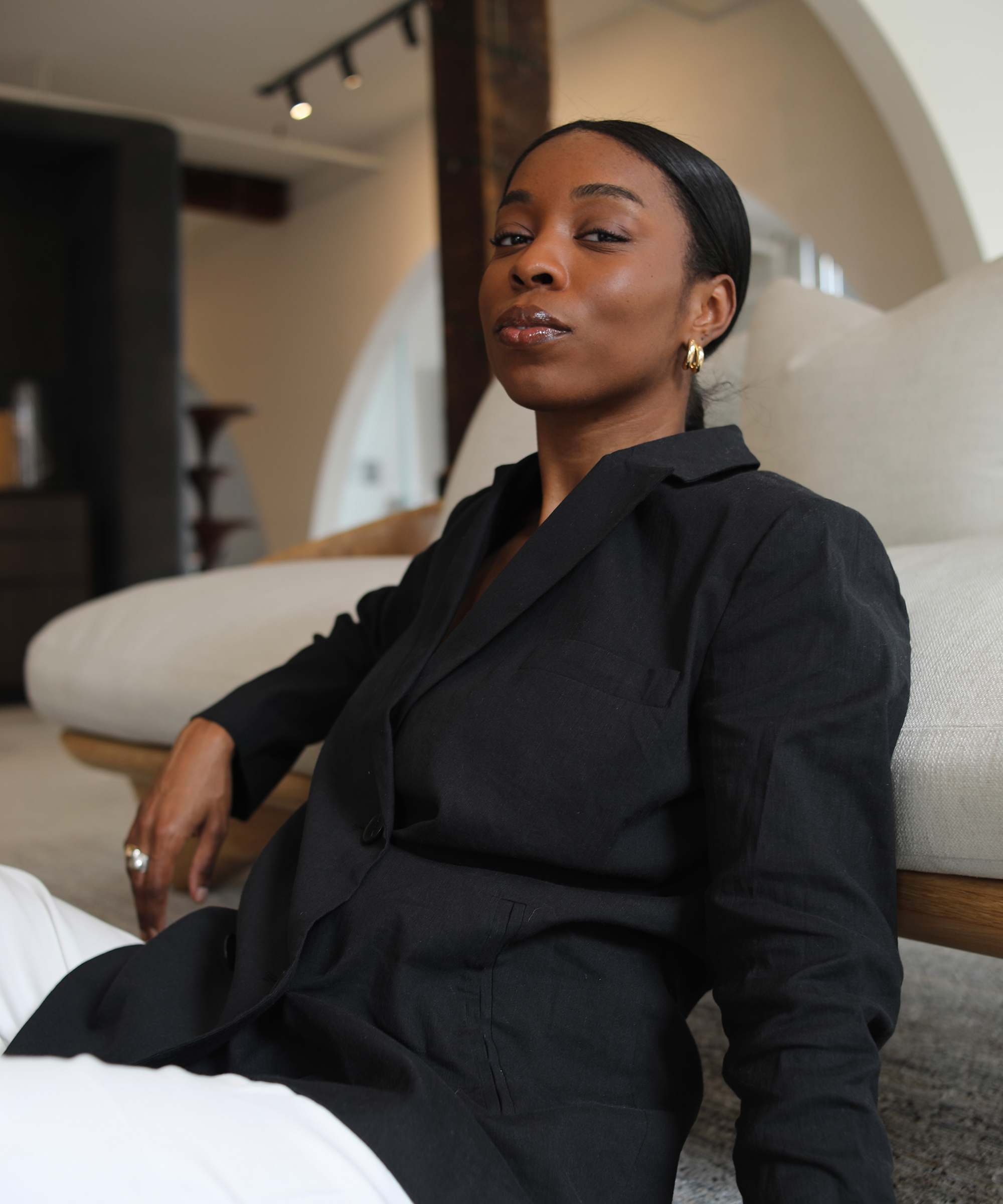 woman leaning against a couch in a black linen blazer