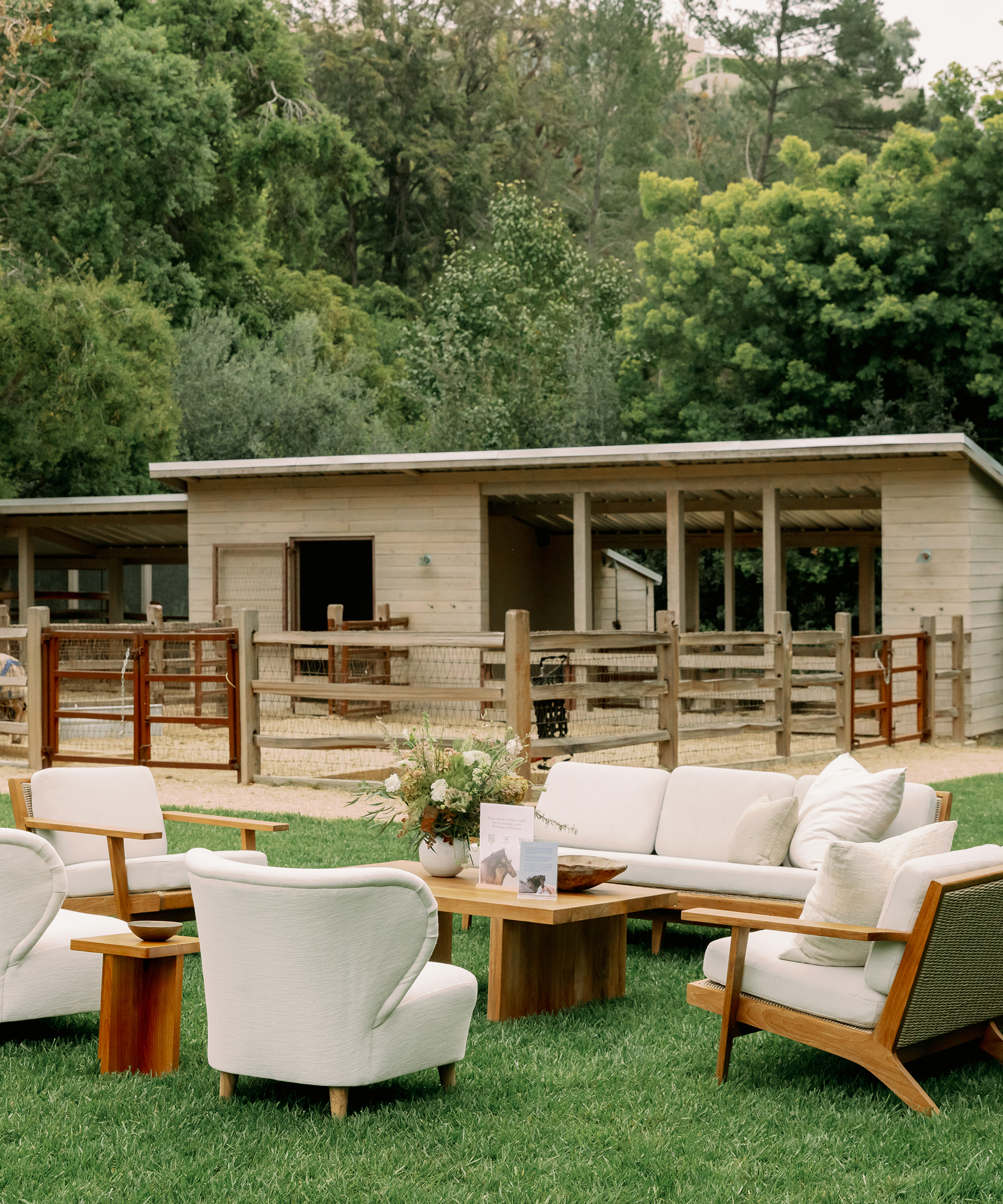 white outdoor vista couch and oak outdoor coffee table in front of barn in the grass