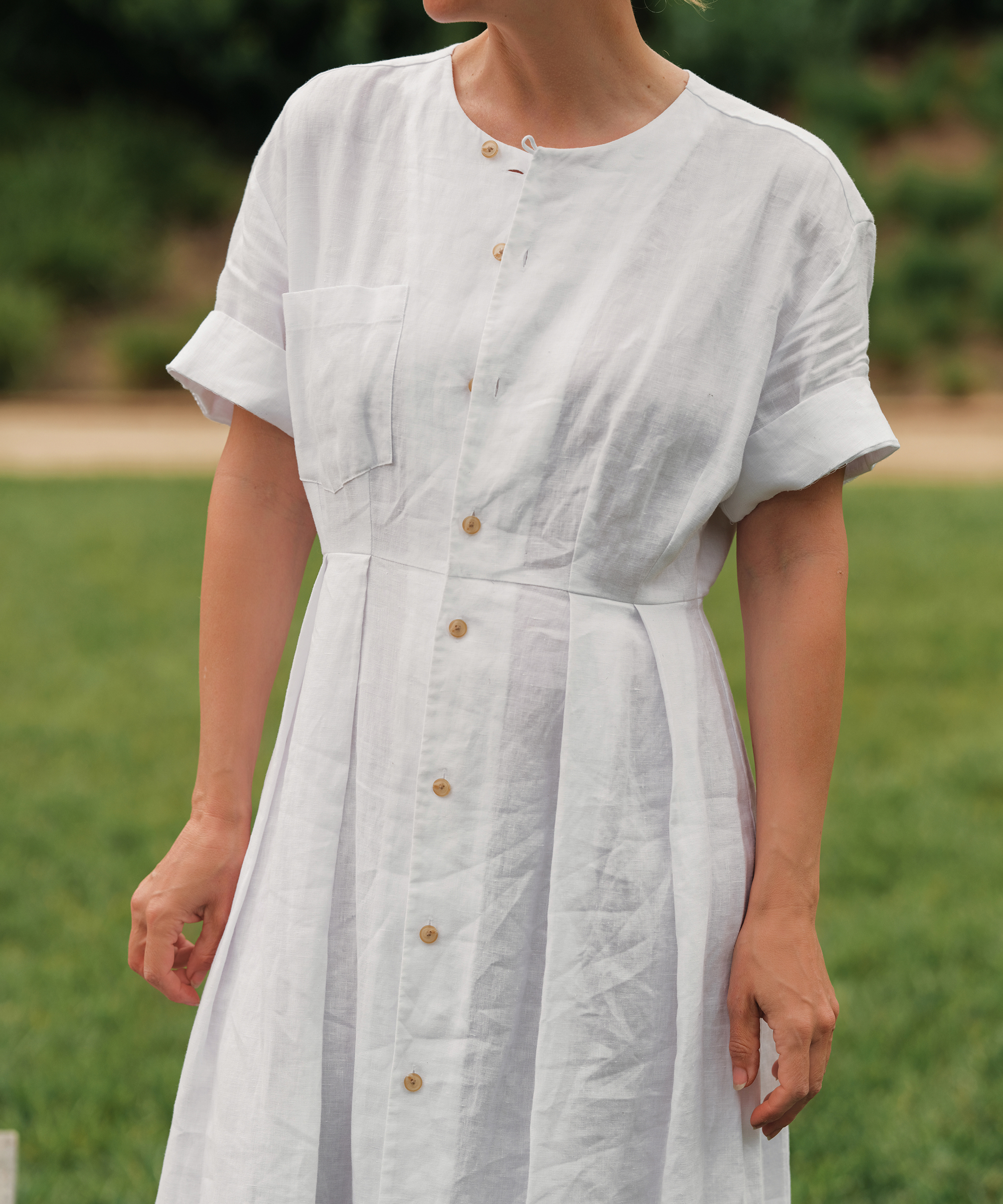 jenni kayne wearing a white linen day dress close up in the grass