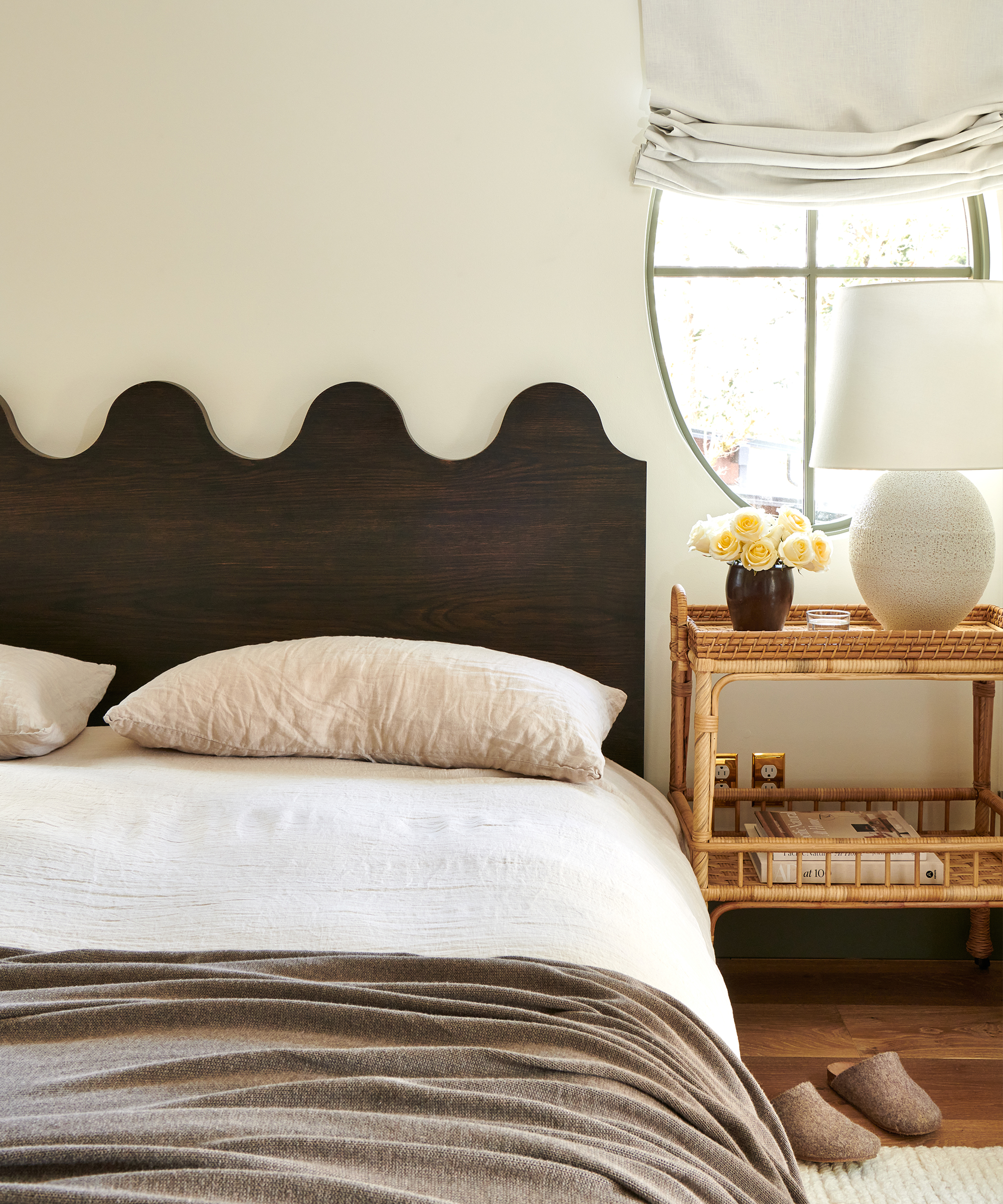 olive green scalloped headboard with a rattan nightstand and ivory table lamp
