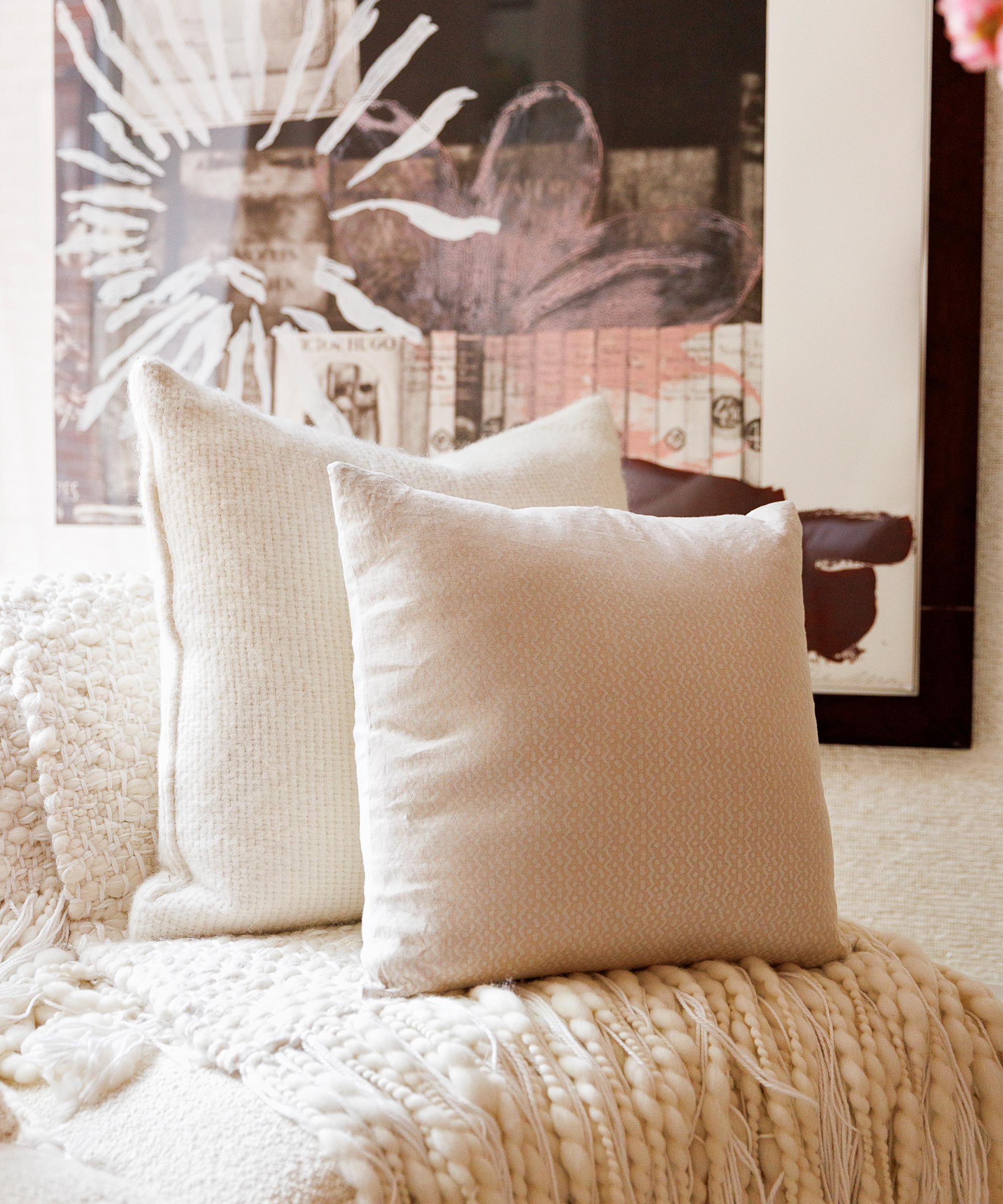 two ivory basketweave pillows on a white couch in front of a mixed media photograph