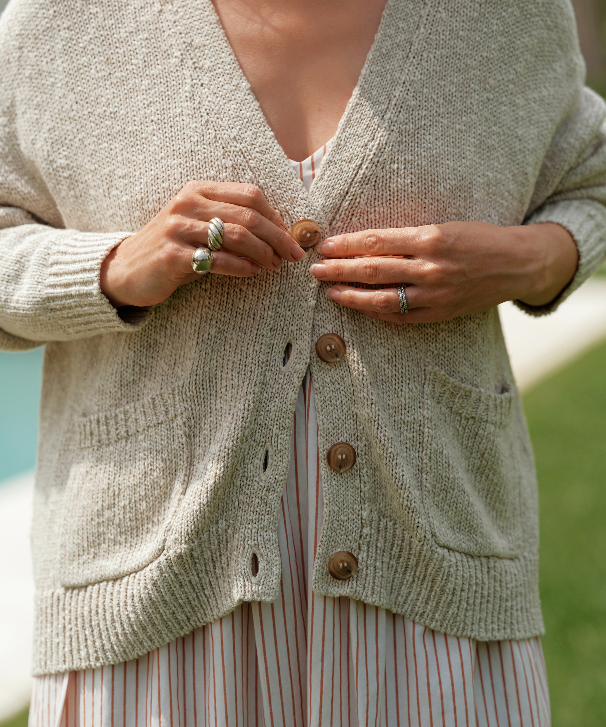 jenni buttoning a natural colored cropped cocoon cardigan over a striped maxi dress