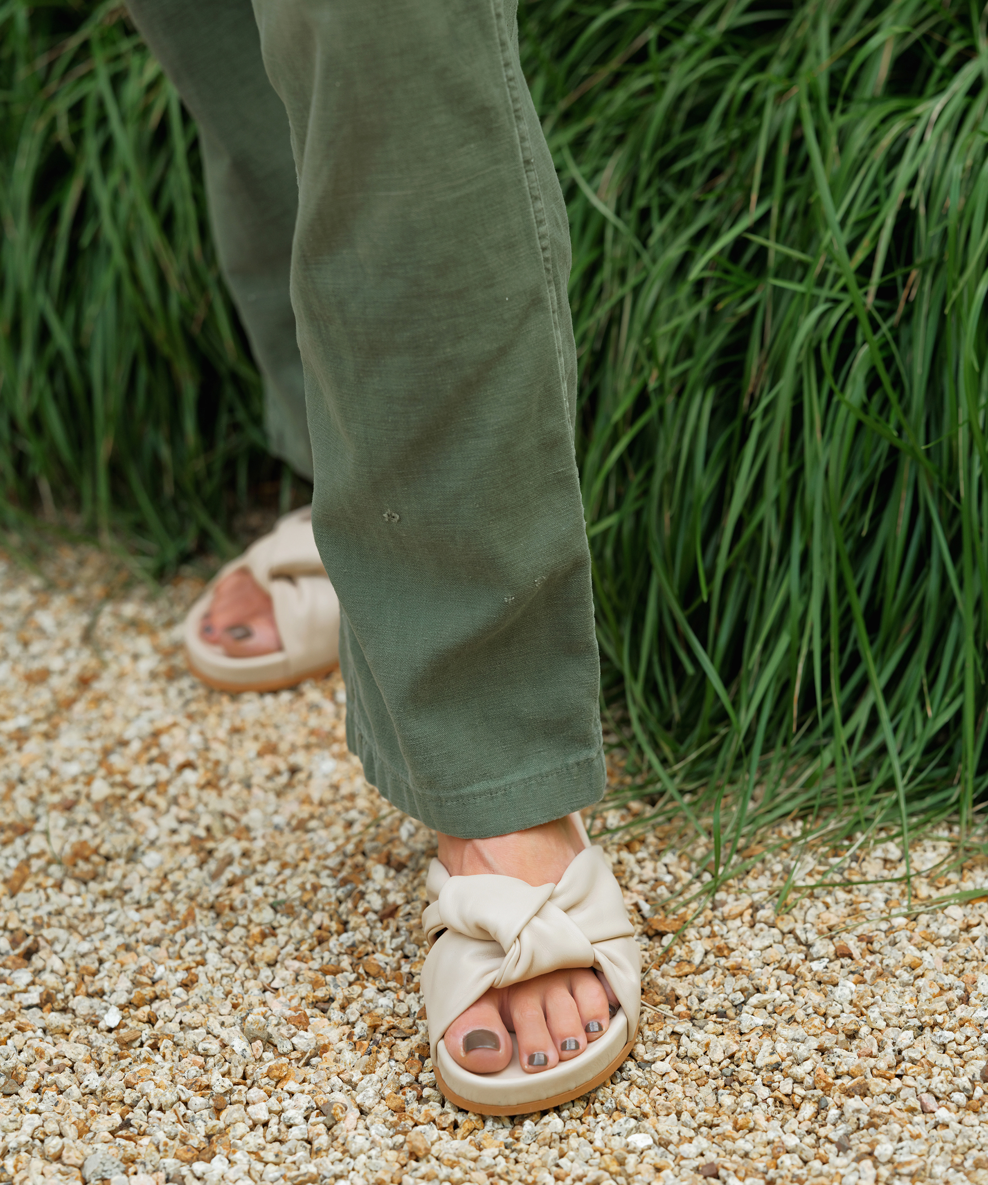 leather knot sandals on gravel with green pants