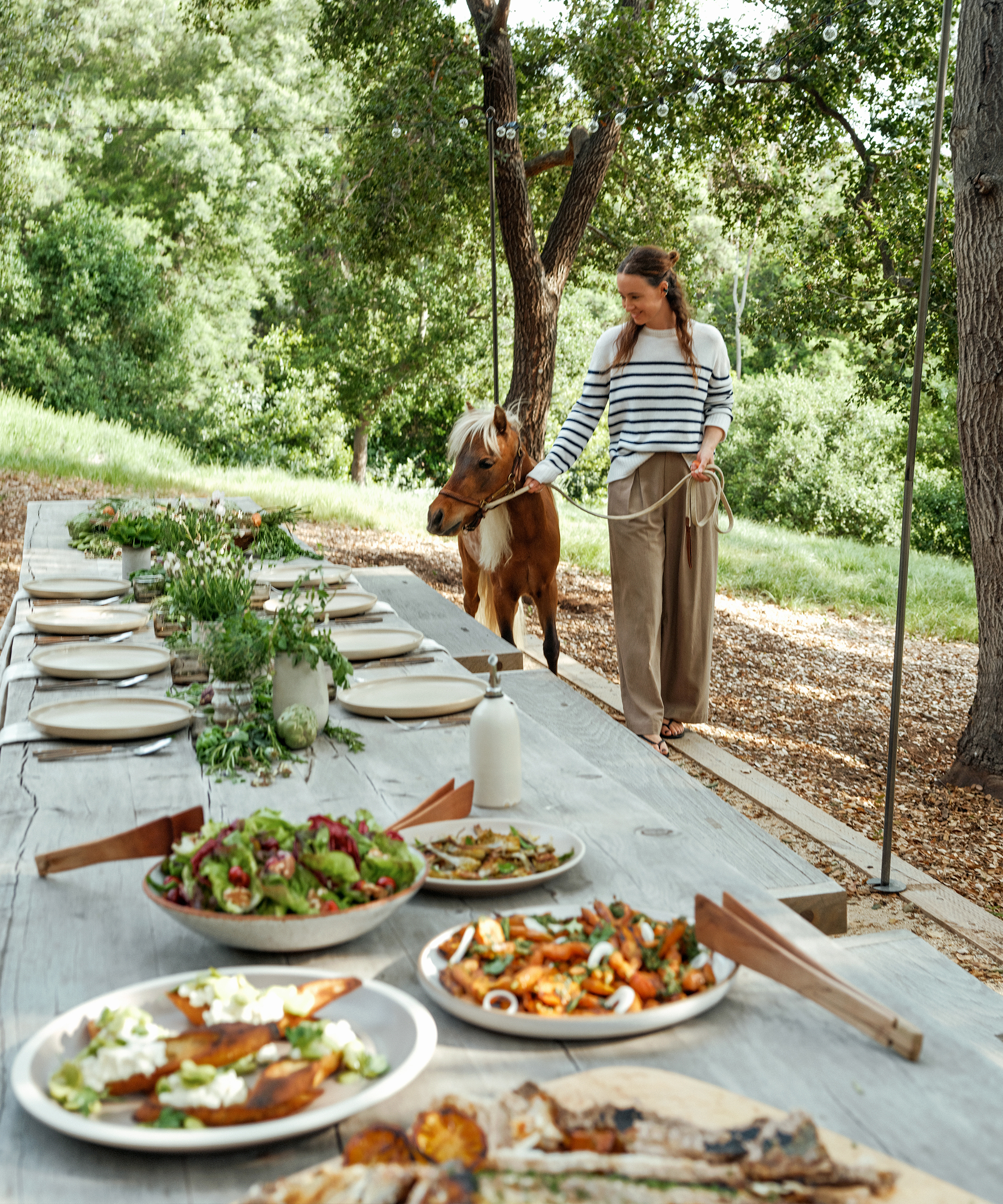 jenni walking her horse to a long outdoor table with simple place settings dinner served on large platters