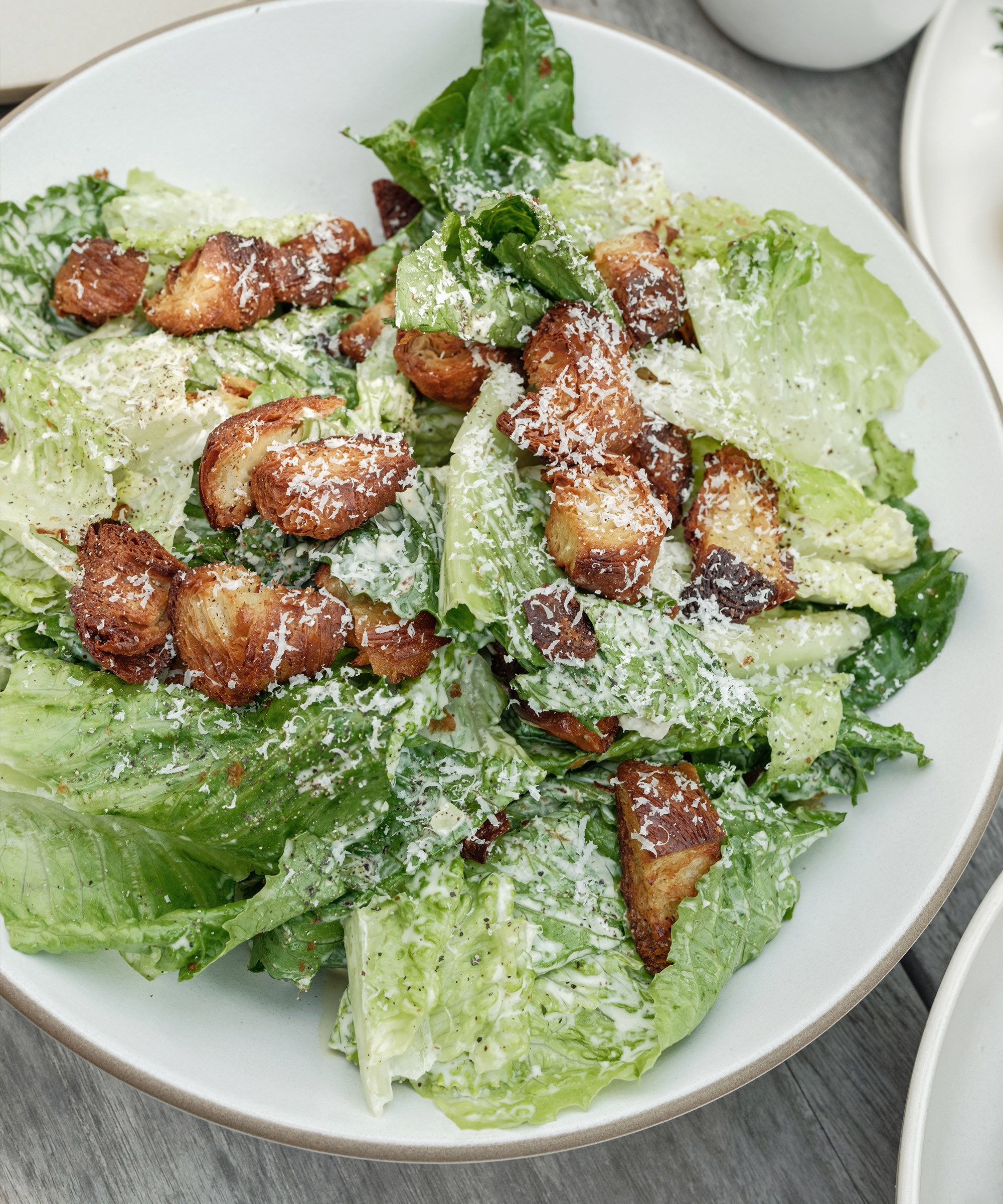 ceasar salad in an ivory serving bowl