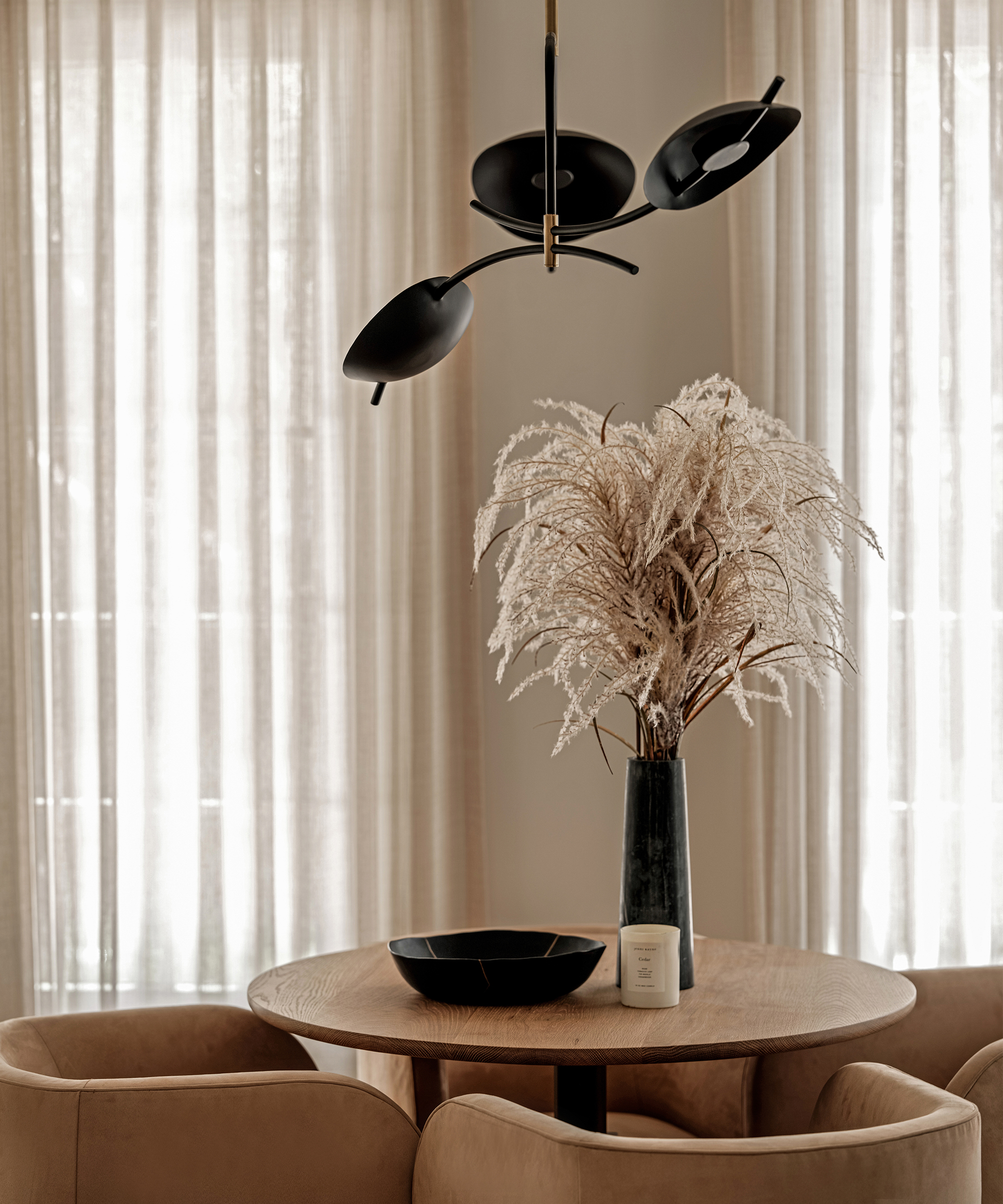 ivory curtains with a round wood table and beige club chairs