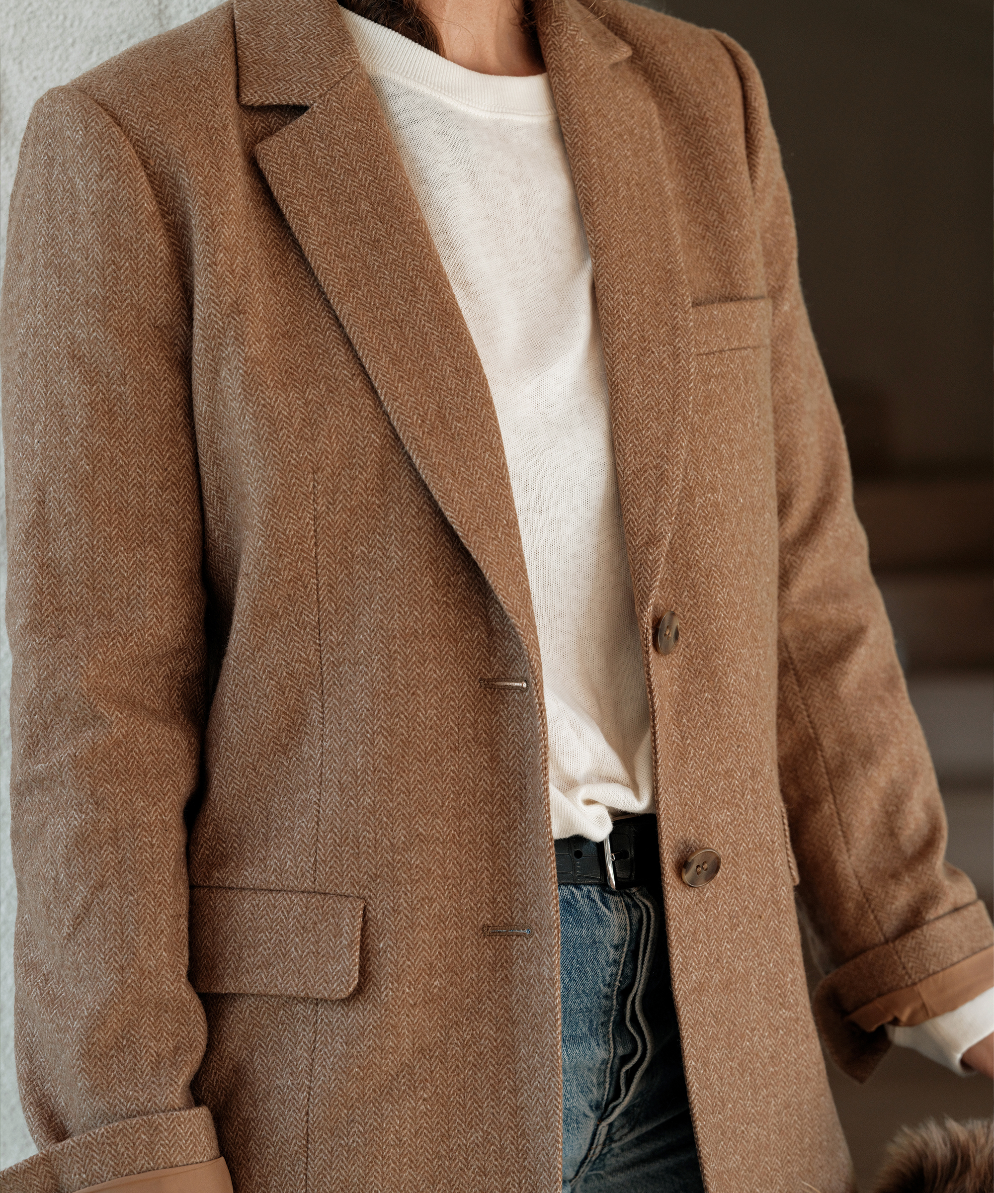 a camel blazer styled with jeans and a white long sleeve tee