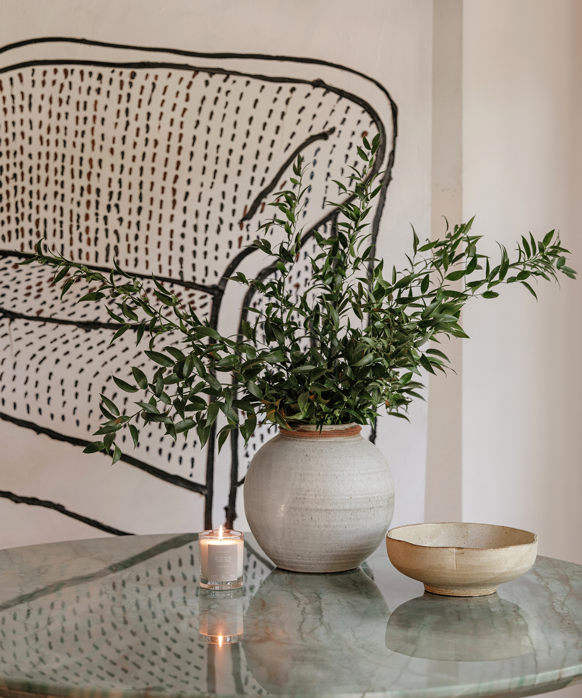 green marble coffee table with a candle burning and a vase with green branches
