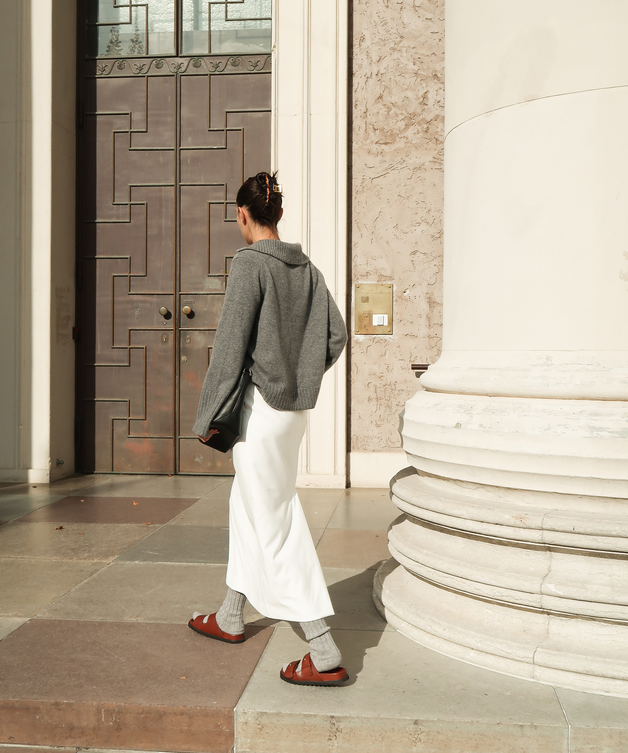 christina stougaard in a grey polo sweater maxi denim creme skirt and socks with tan leather sandals