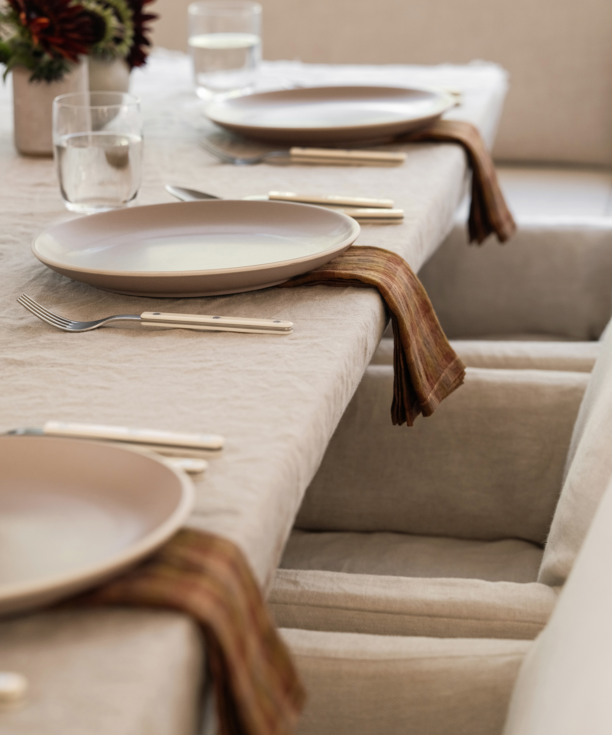 light grey ceramic plates with ivory cutlery and plaid napkins on a taupe tablecloth