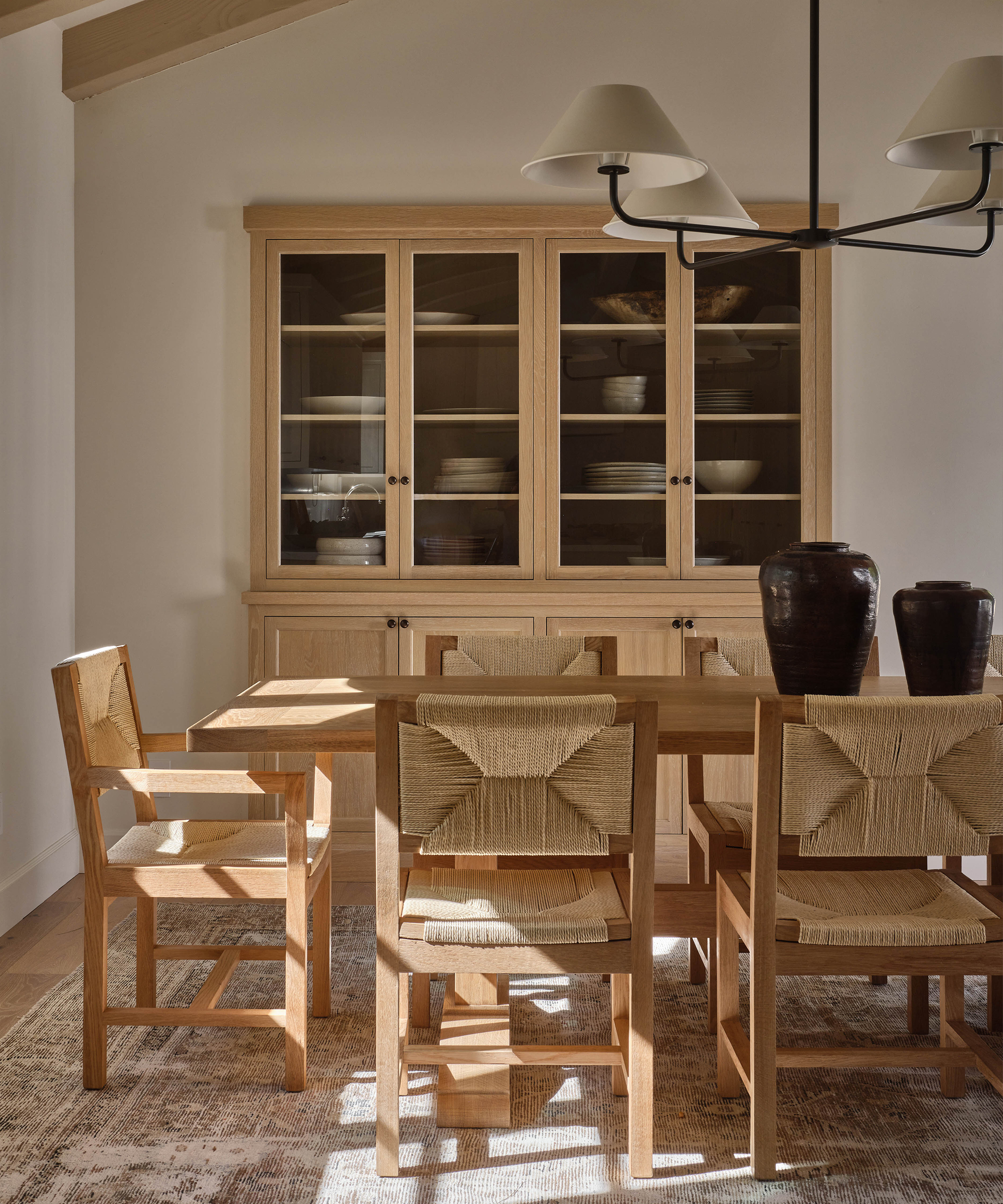 a dining room with a wood dining table and wooden dining chairs next to a wood bar cabinet