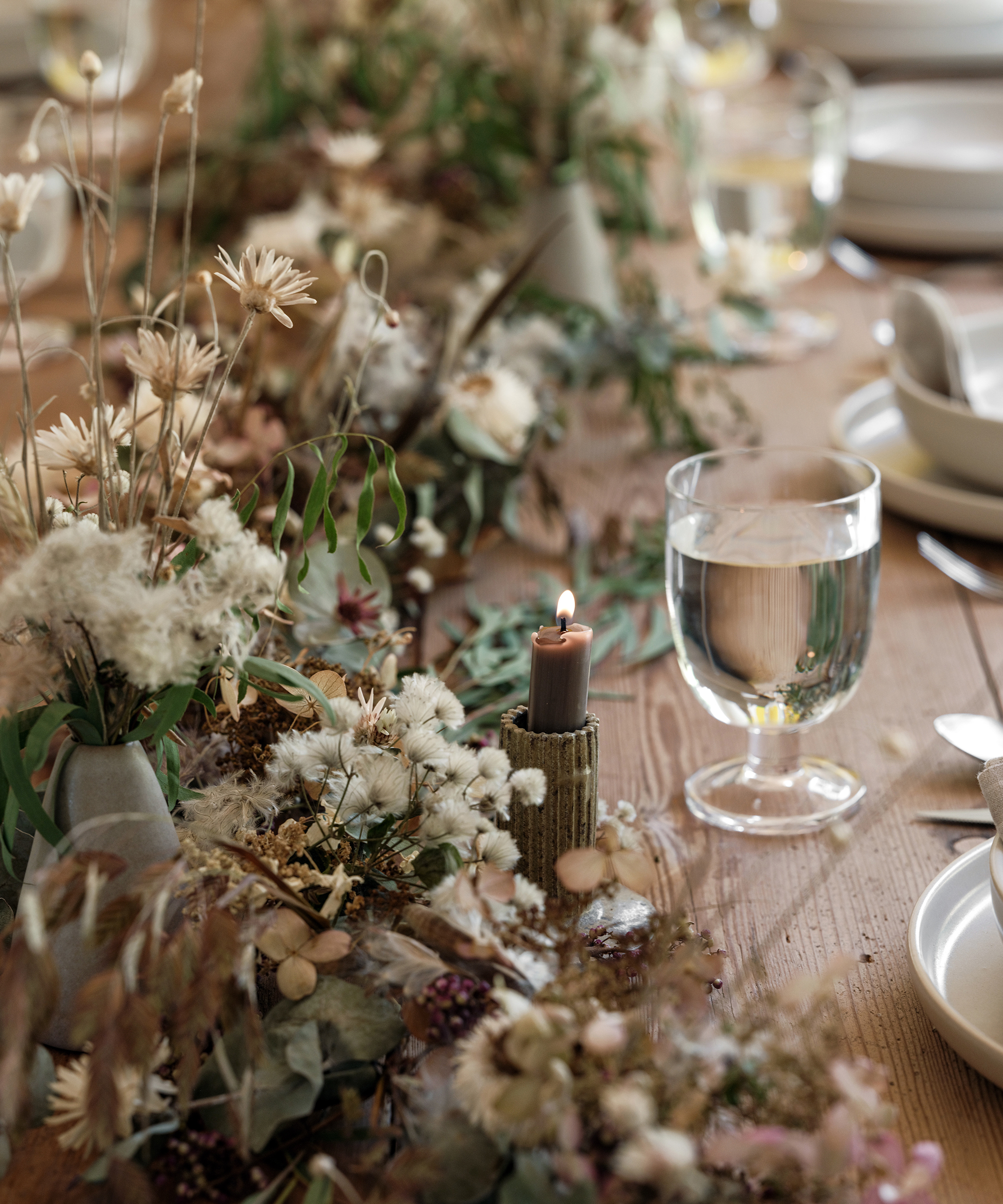 a wood dining table with fall inspired florals sprawled down the tabel