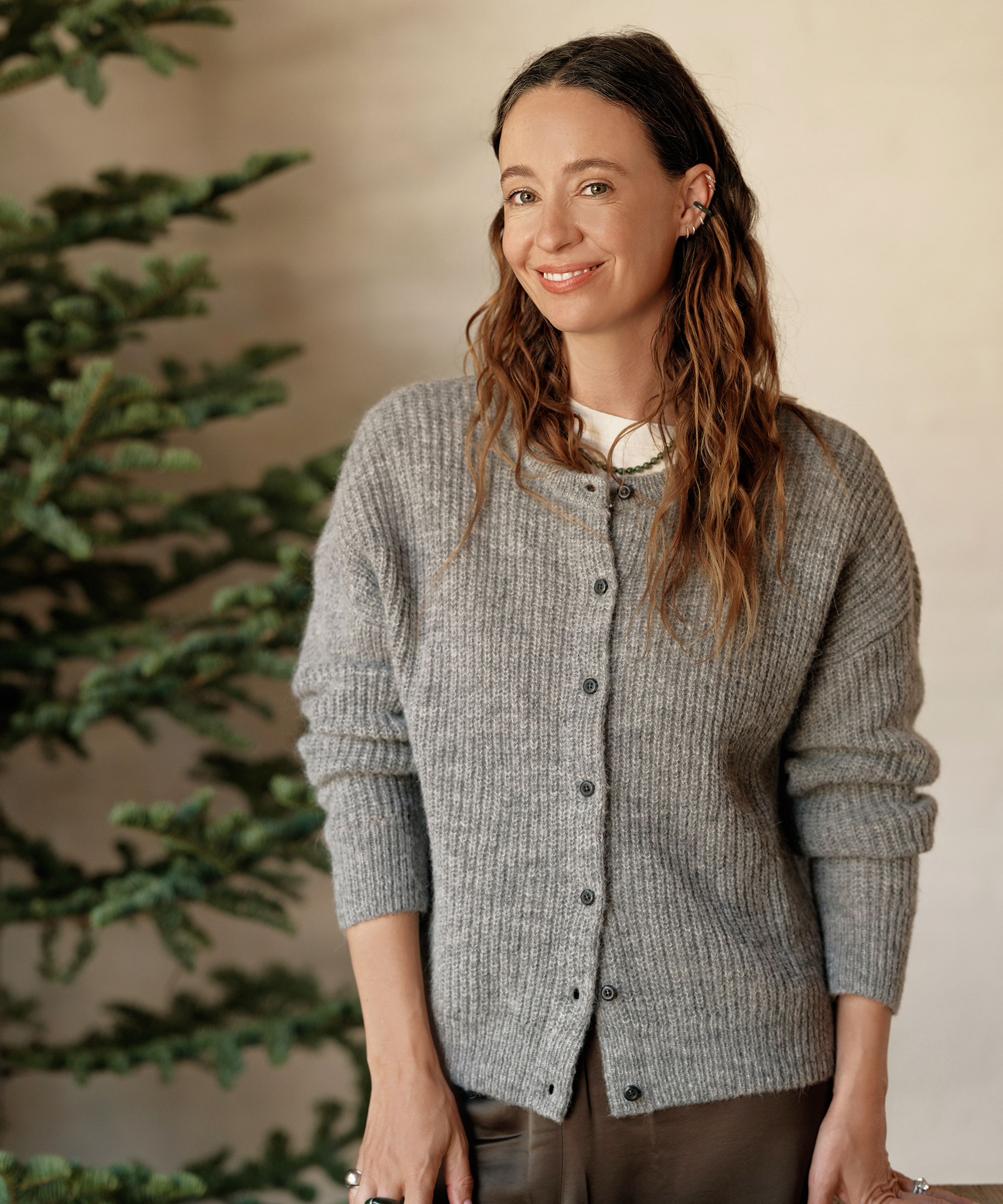 jenni in a grey cardigan standing in front of an ivory wall