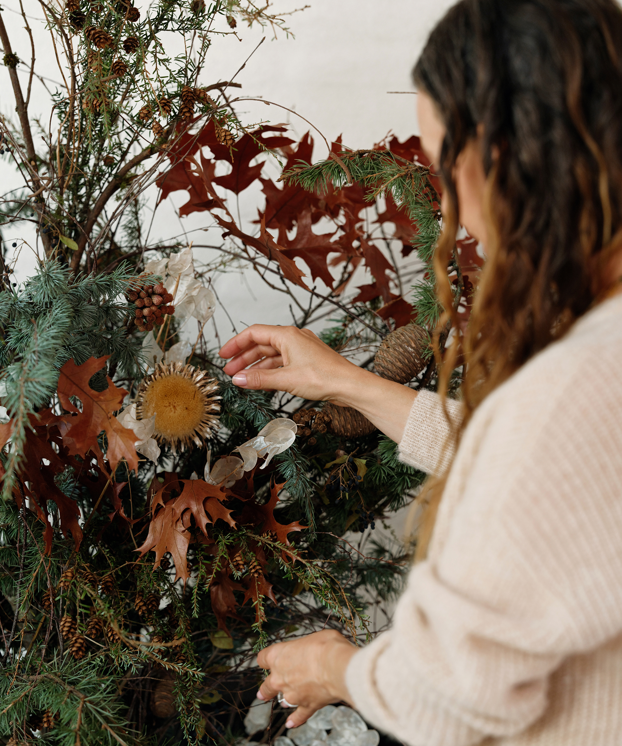 jenni fixing up a green and orange leaves garland on her ivory brick mantle