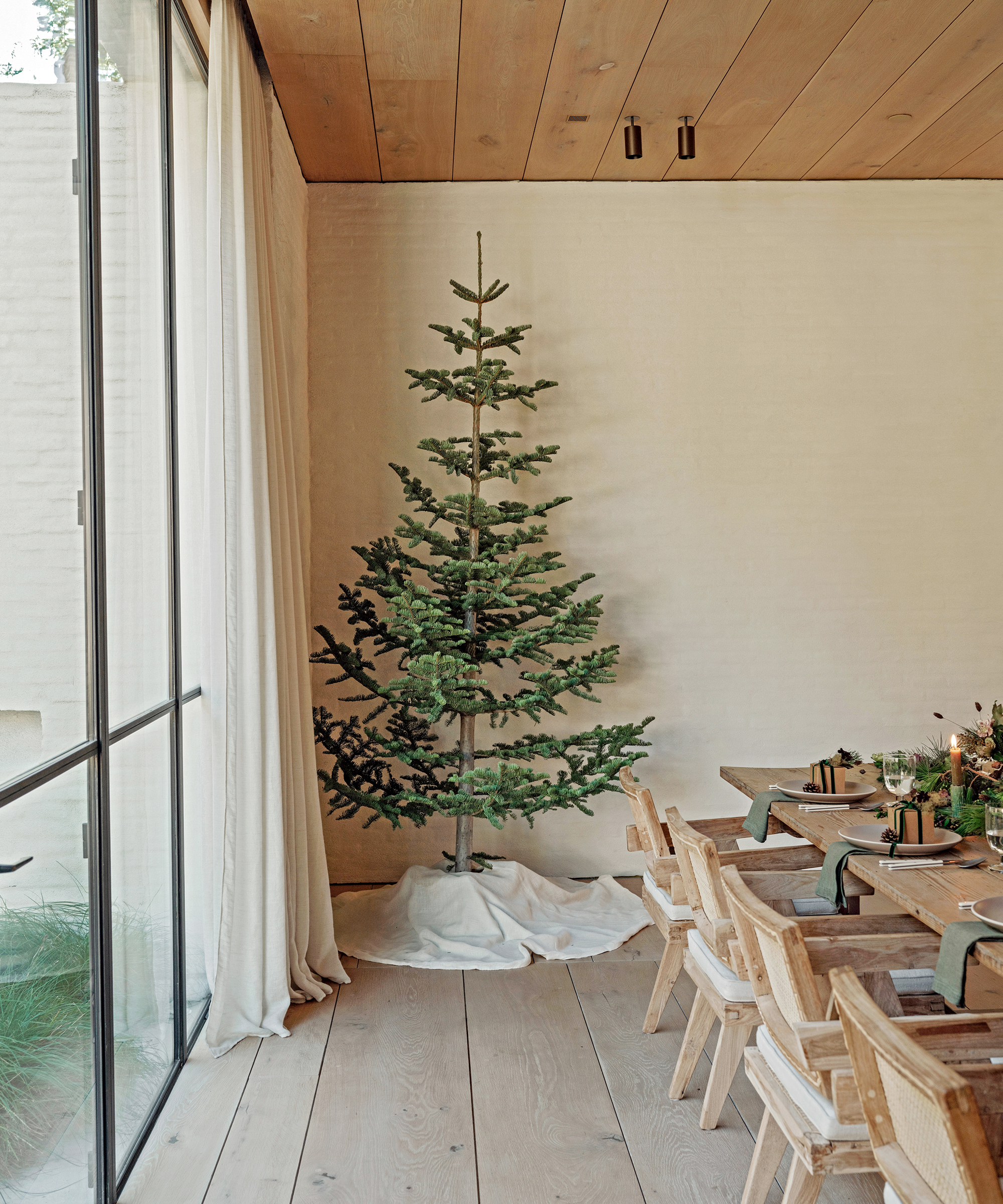 a dining room with a bare christmas tree and an ivory tree skirt