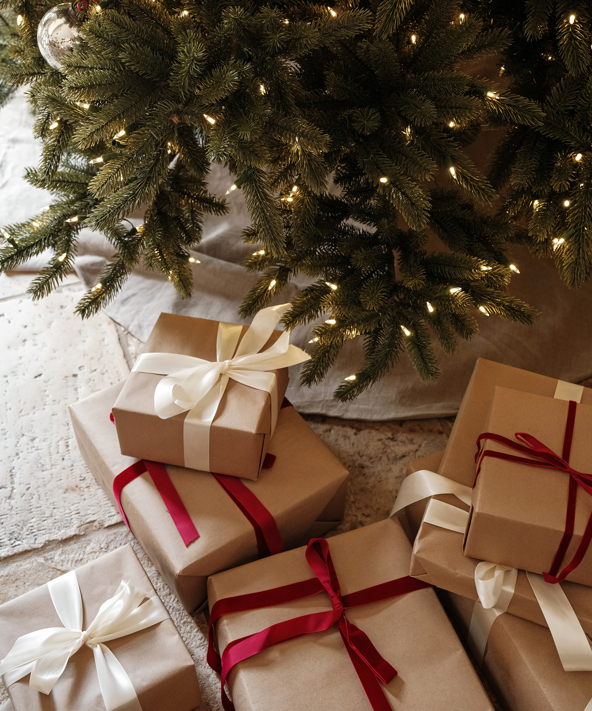 presents wrapped in brown paper and red ribbon under the christmas tree