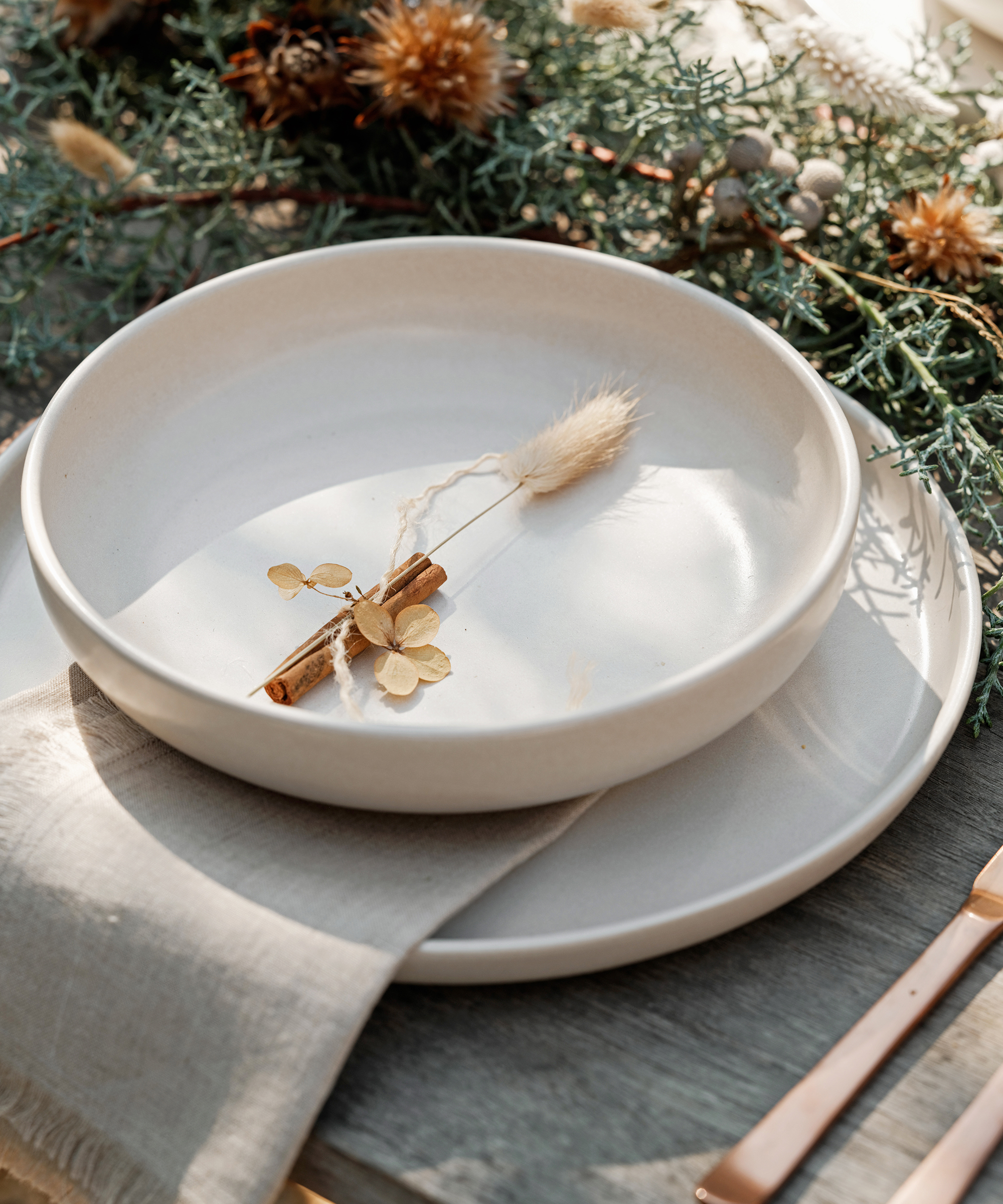 ivory soup bowl and dinner plate with a linen napkin and a piece of wheat on the dinnerware