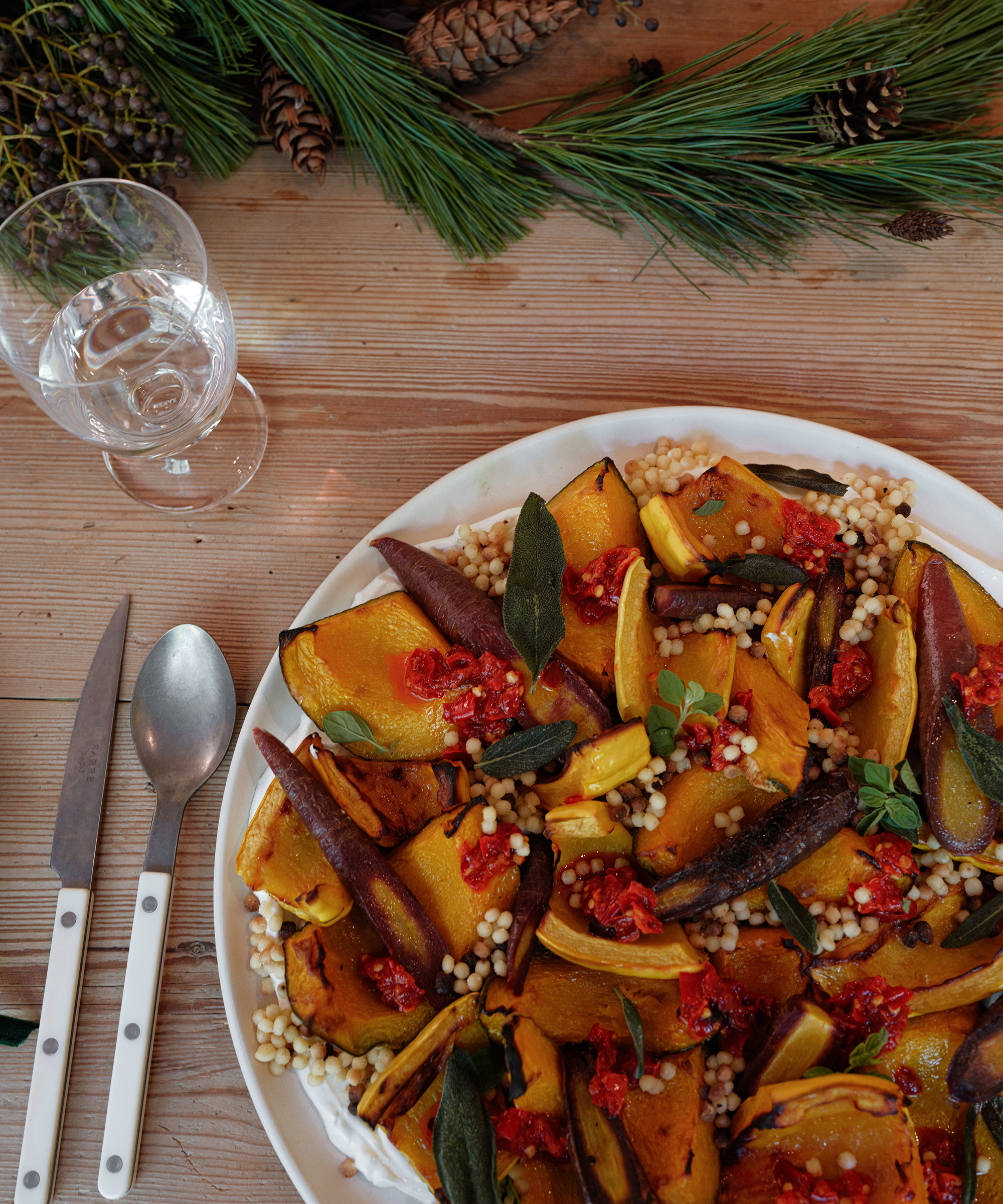 a colorful squash dish on an ivory platter on a wooden dining table