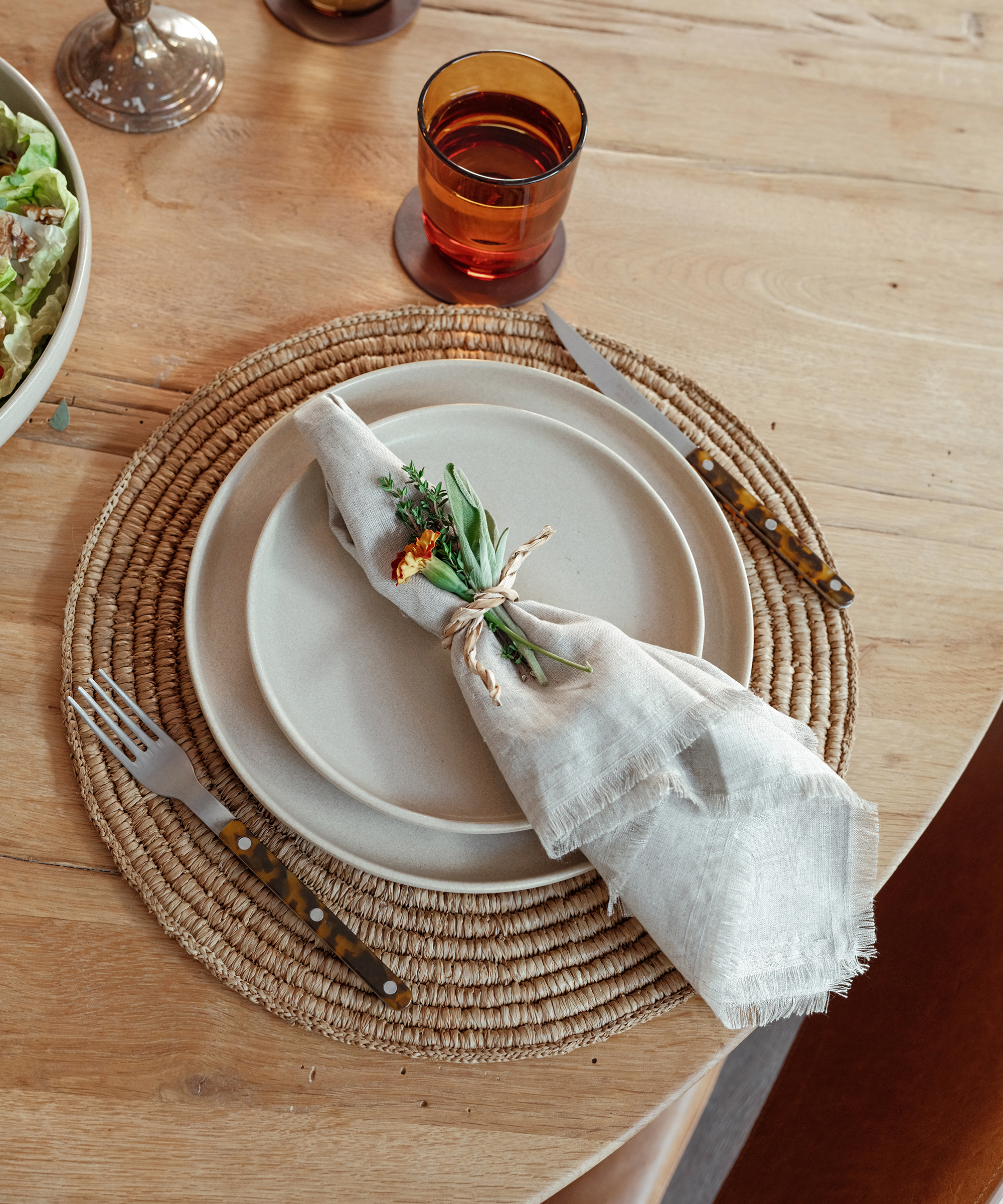 ivory pacific plates on a woven charger on a wooden dining table with a linen napkin