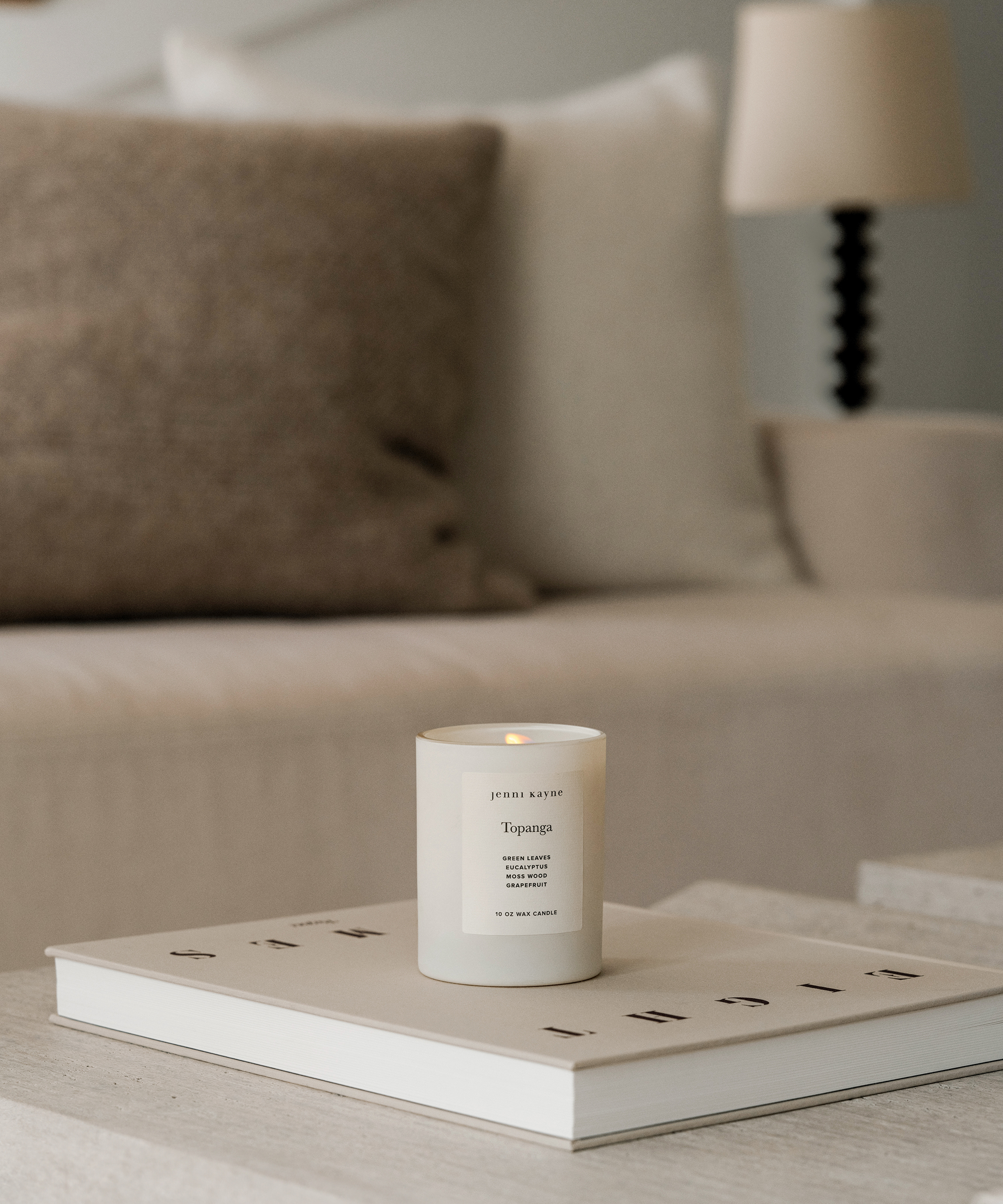a living room with a travertine coffee table styled with a coffee table book and candle