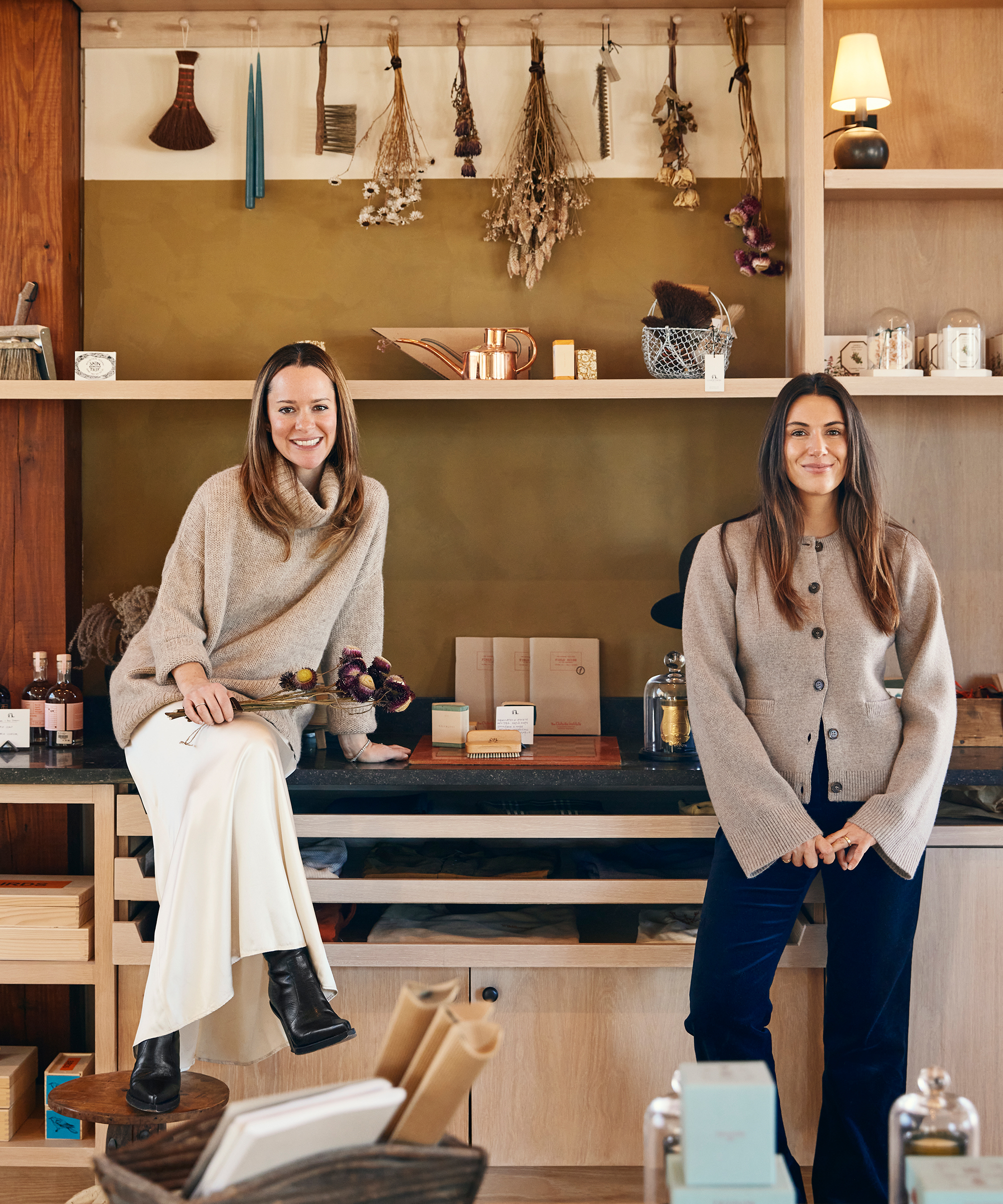 two women in taupe sweater sitting on a counter with tools