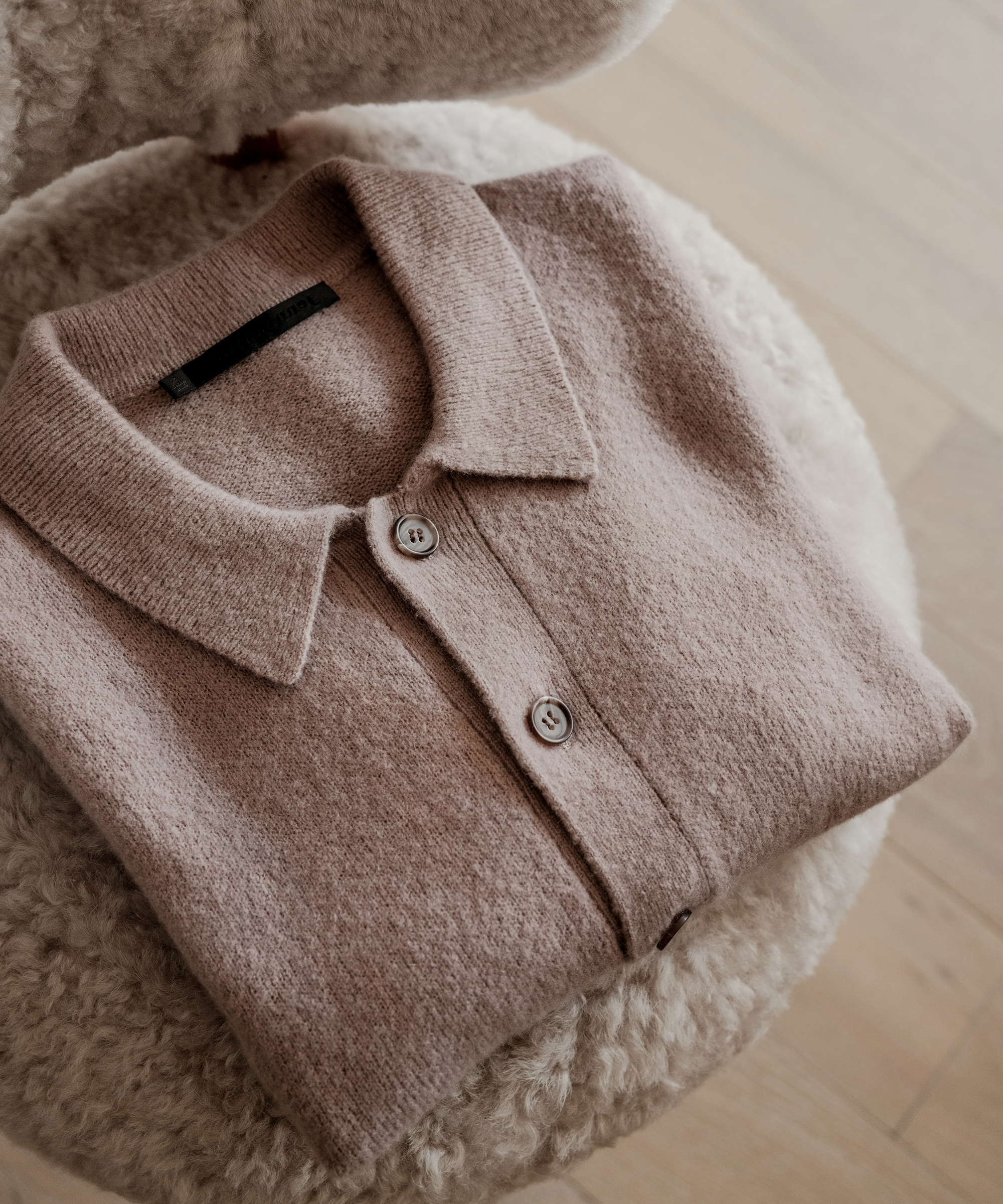 collared cashmere sweater folded on a shearling accent chair