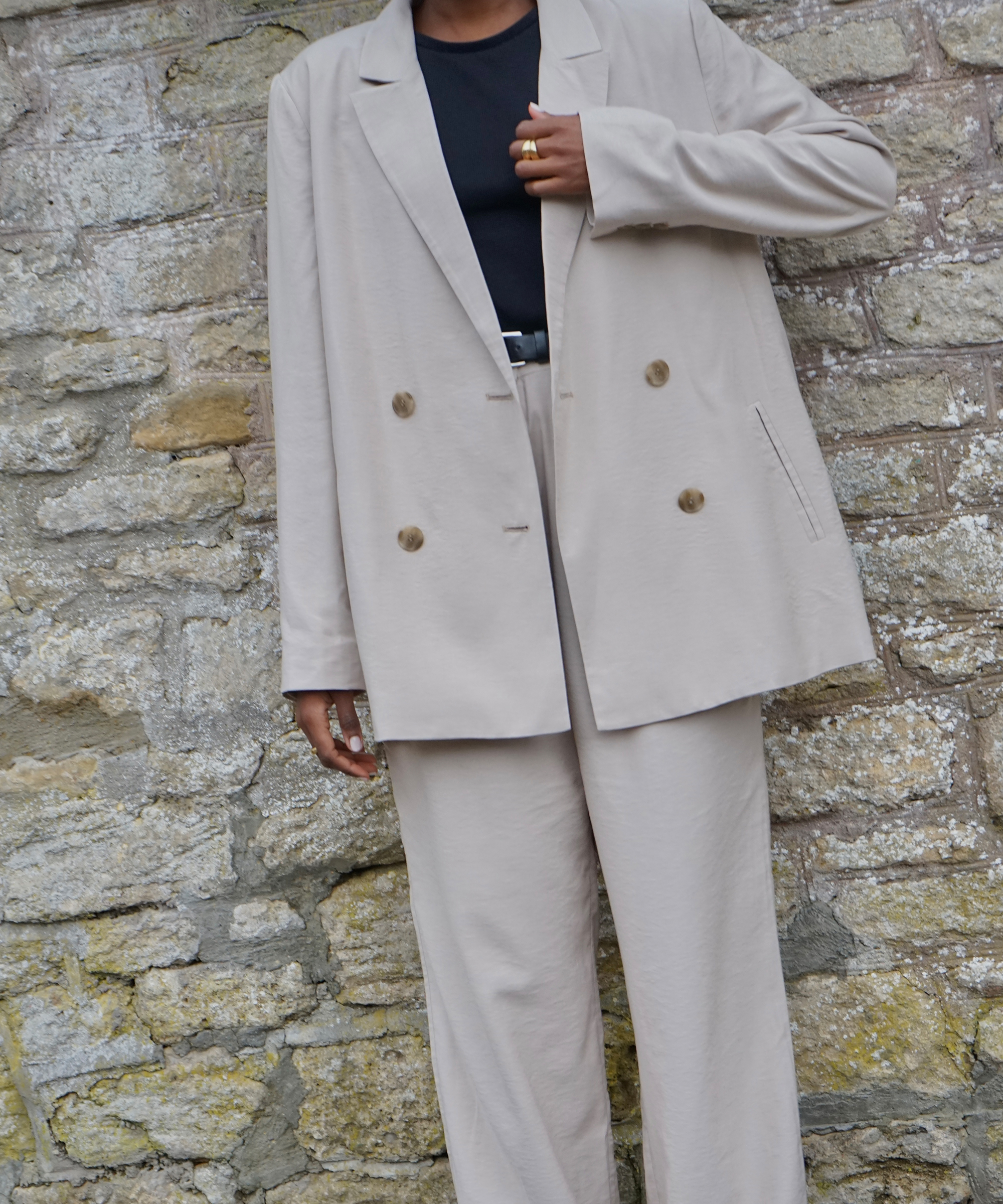 a tan blazer with a black tee and tan matching trousers