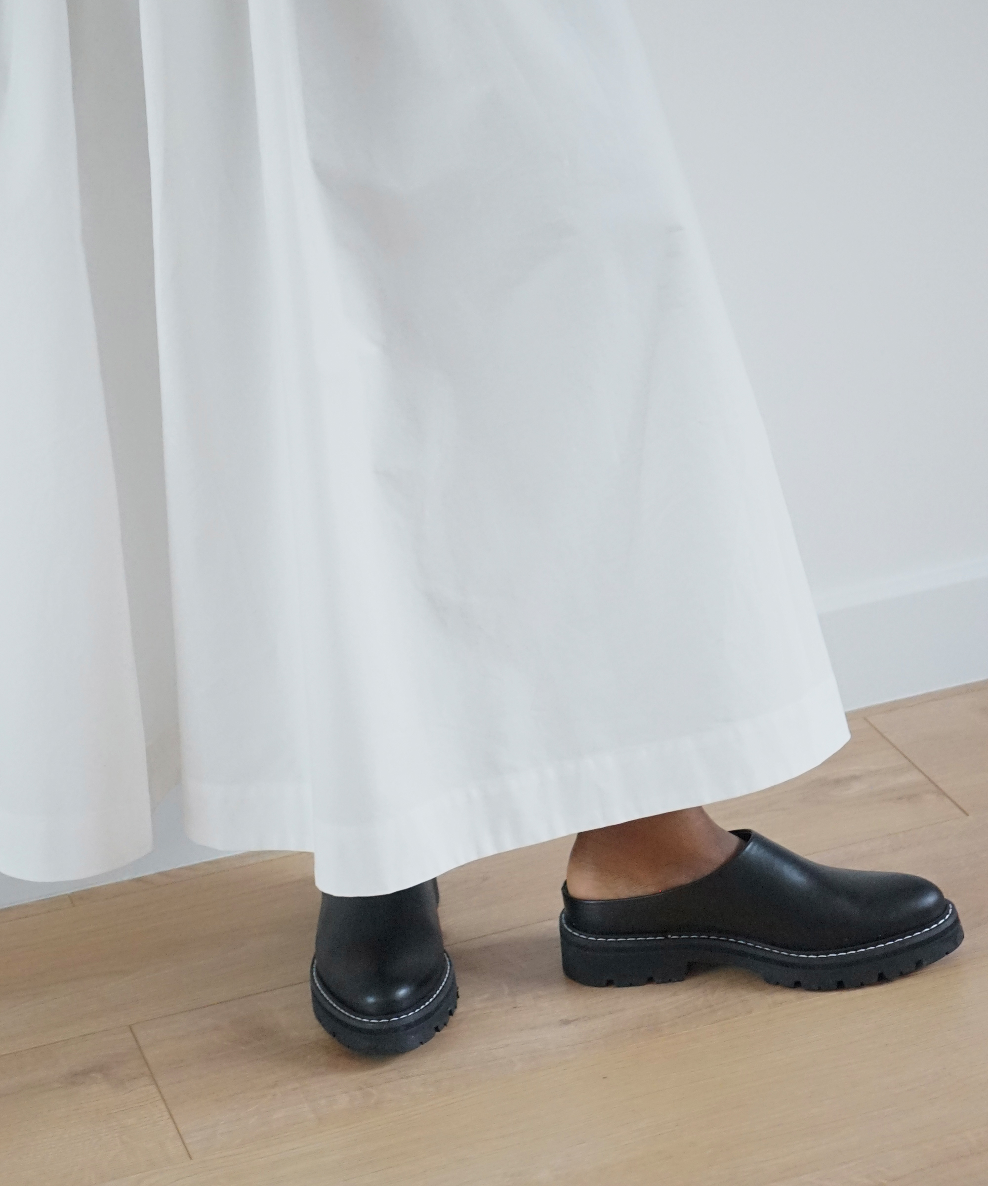 a white cotton skirt with black leather lug mules