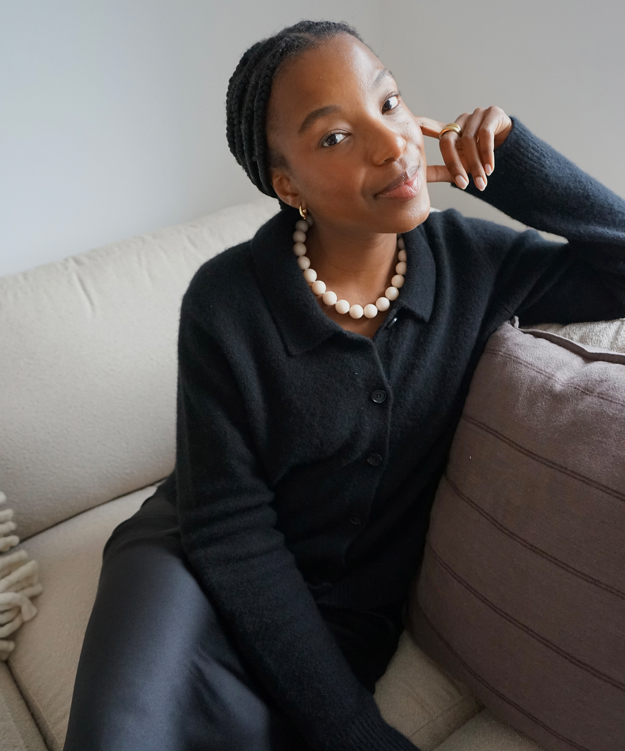 taffy in the black murphy cardigan styled with a black silk skirt sitting on a couch