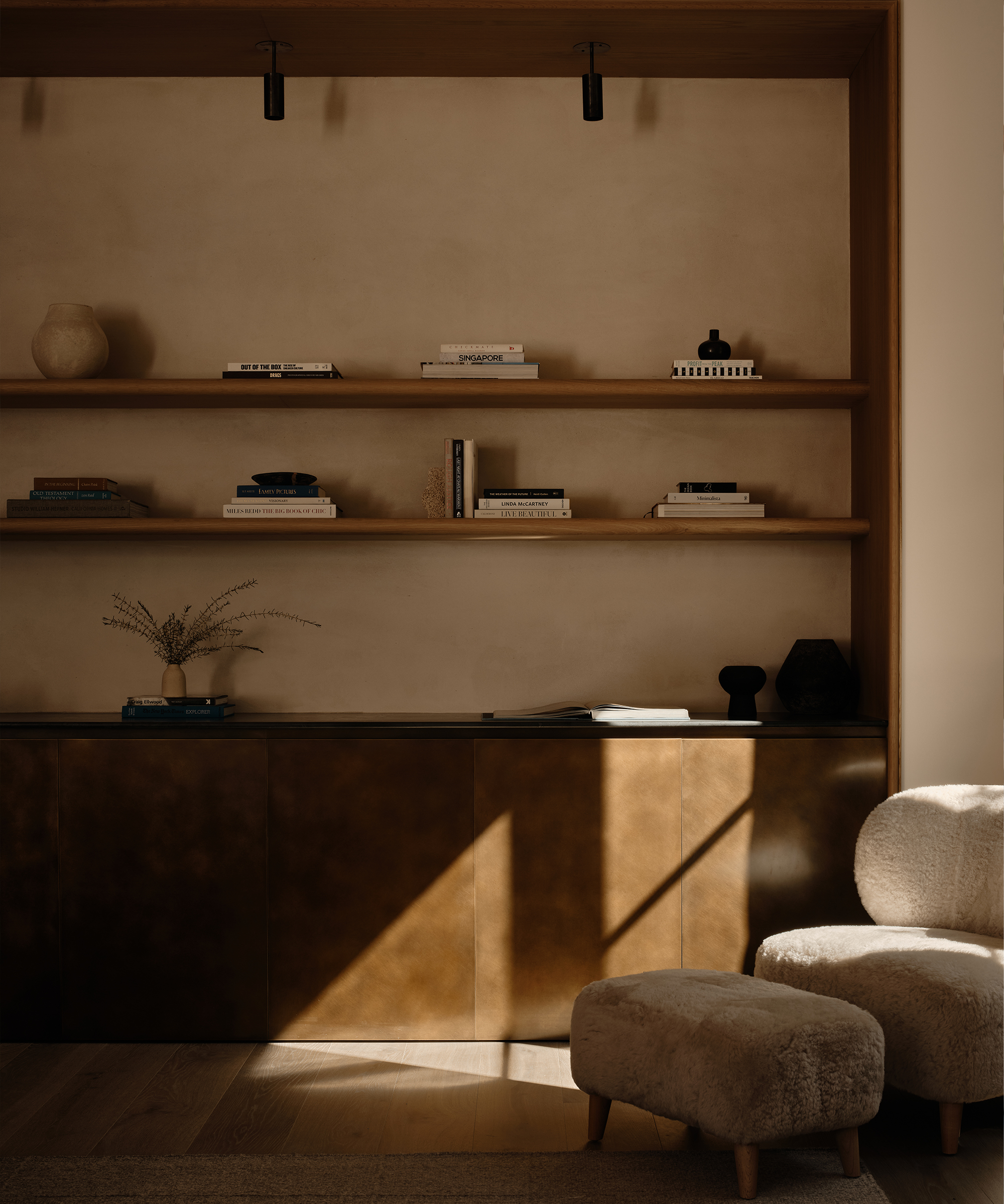 a metal bookcase styled with books and a shearling accent chair with a shearling ottoman
