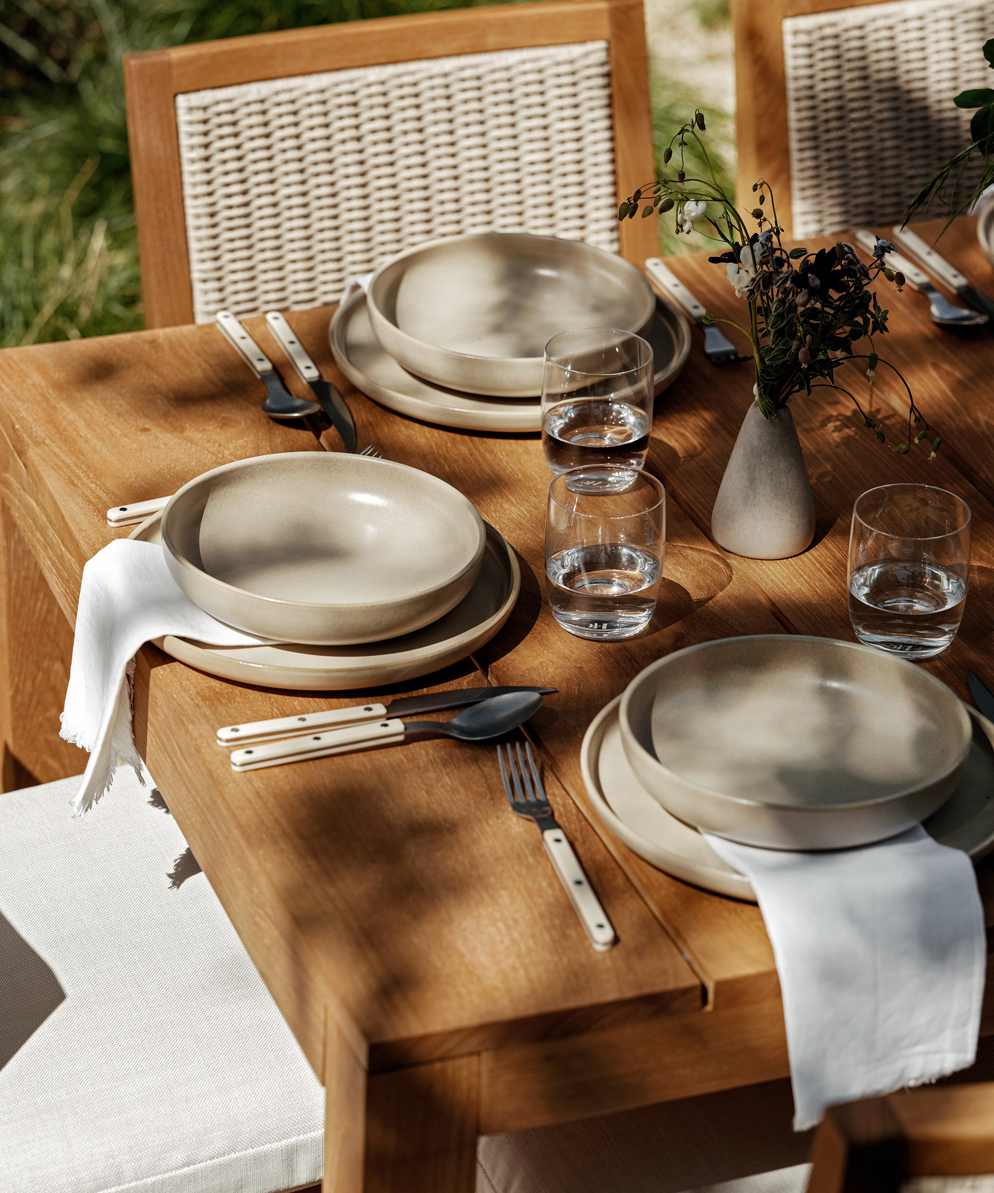 an outdoor dining table with taupe pacific dinner plates and ivory bistro vintage cutlery