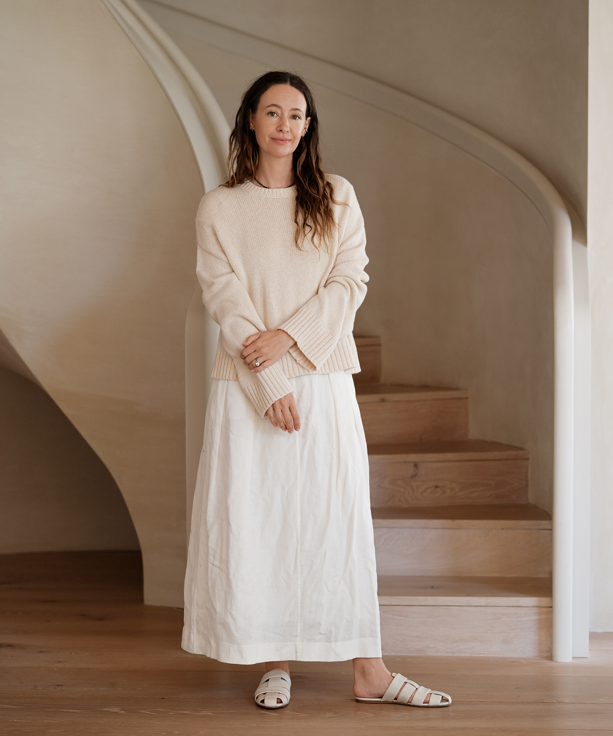 jenni standing next to a stairwell in a white maxi linen skirt and ivory sweater with ivory camilla mules