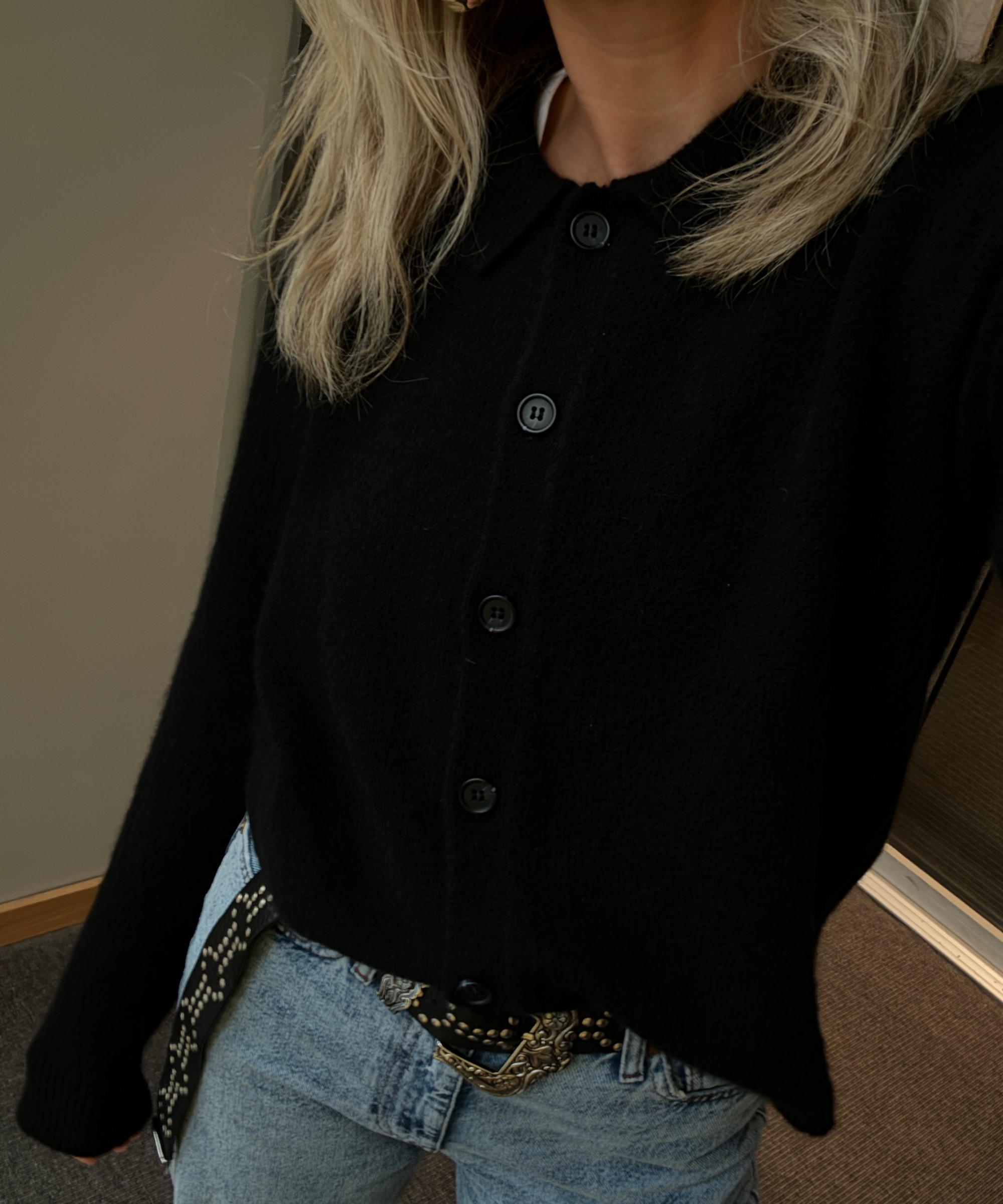 lucy williams in black cardigan and jeans with a statement belt